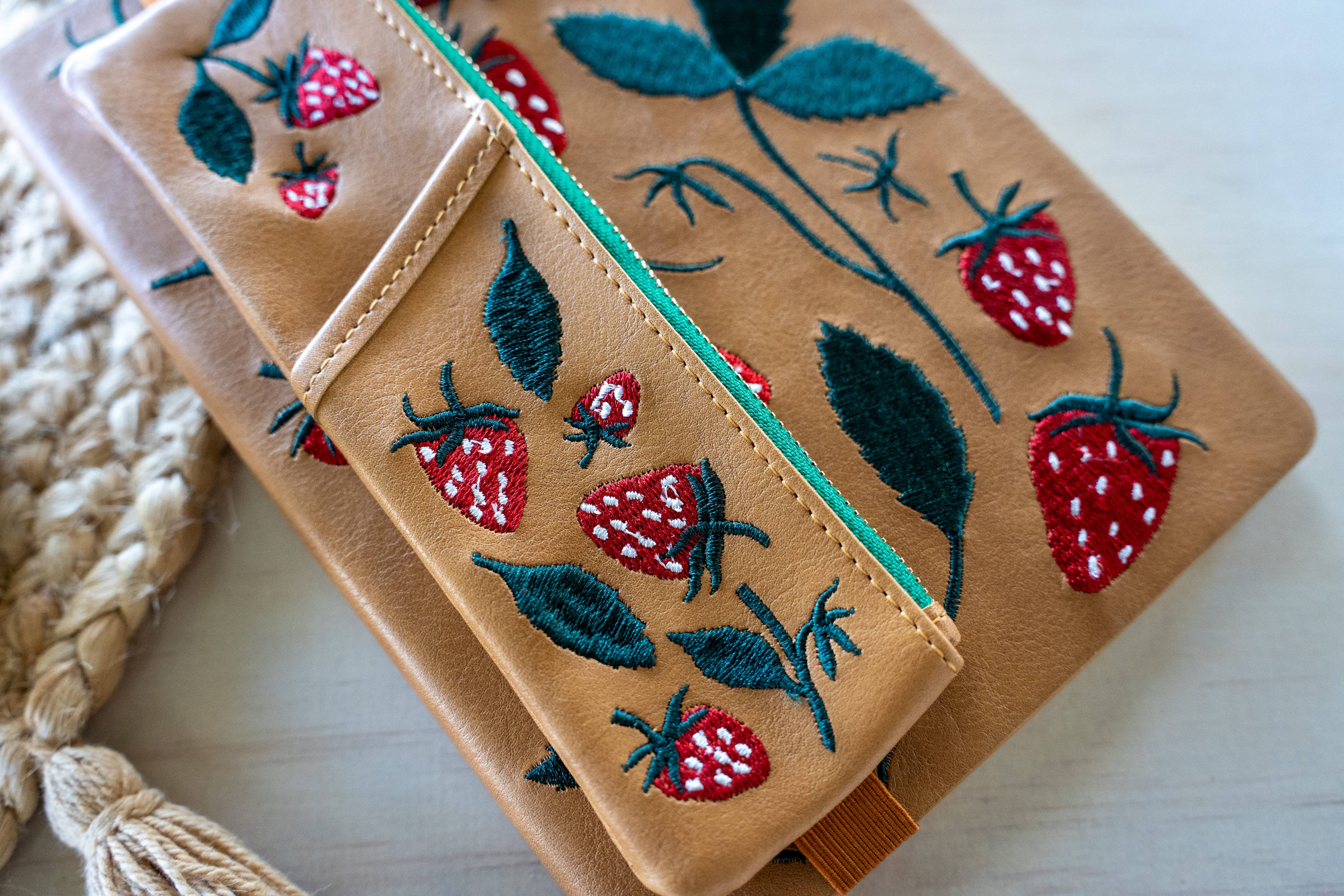 Embroidered wallet with strawberry design on a light background