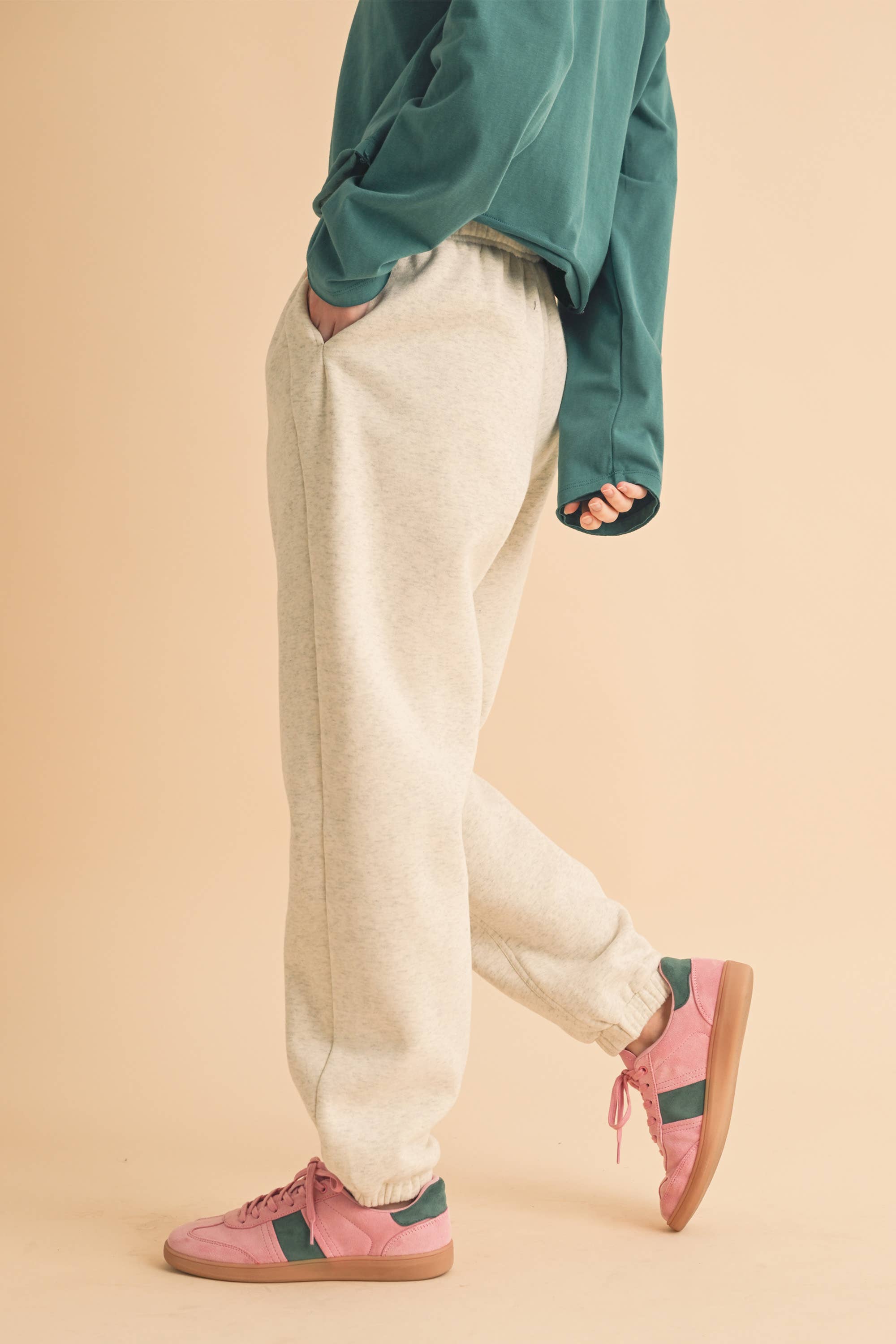 Woman wearing light heather beige fleece jogger pants with a relaxed fit and elastic waistband.