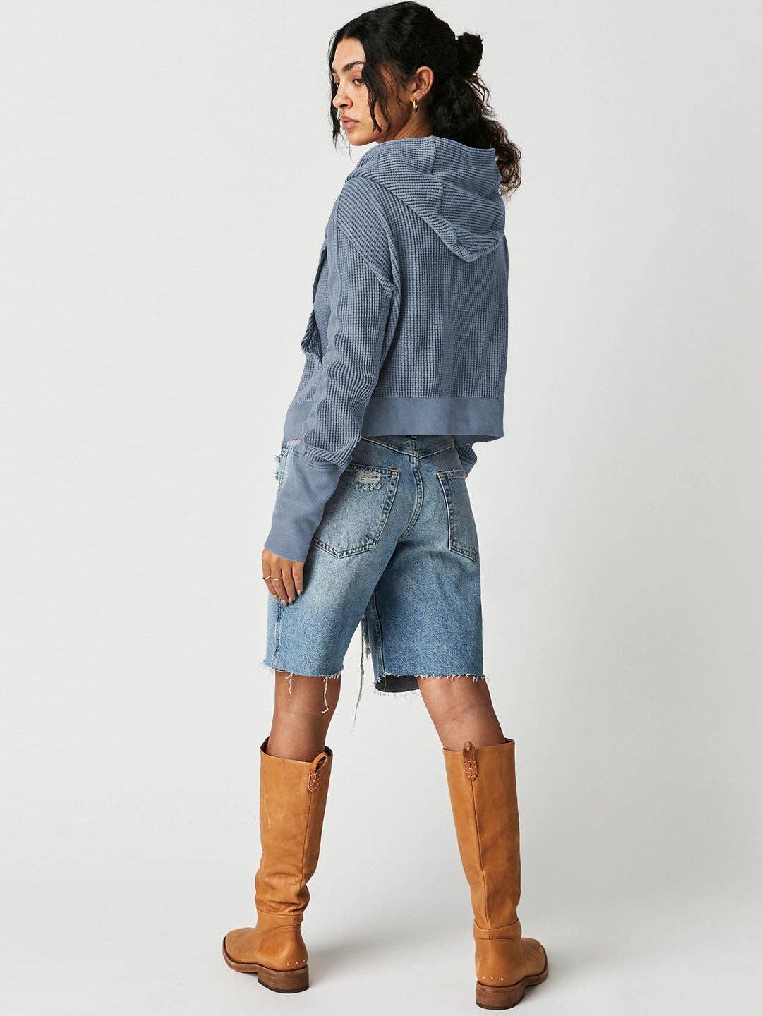 Woman wearing a Sahara Sky Hooded Jacket with a zip-up front, textured waffle knit, and button detailing in blue and brown tones.