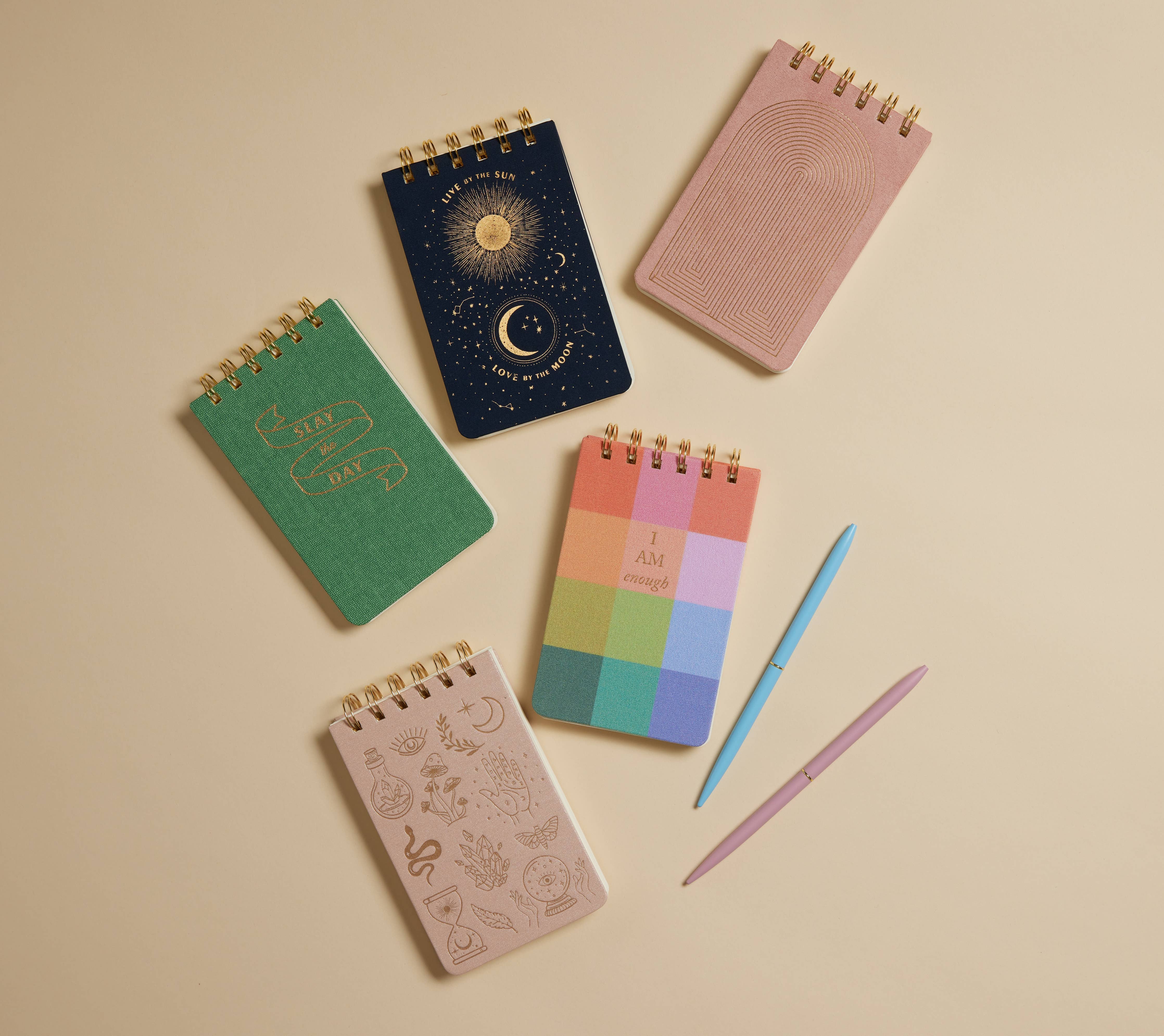Collection of colorful notebooks and a pen on a beige background