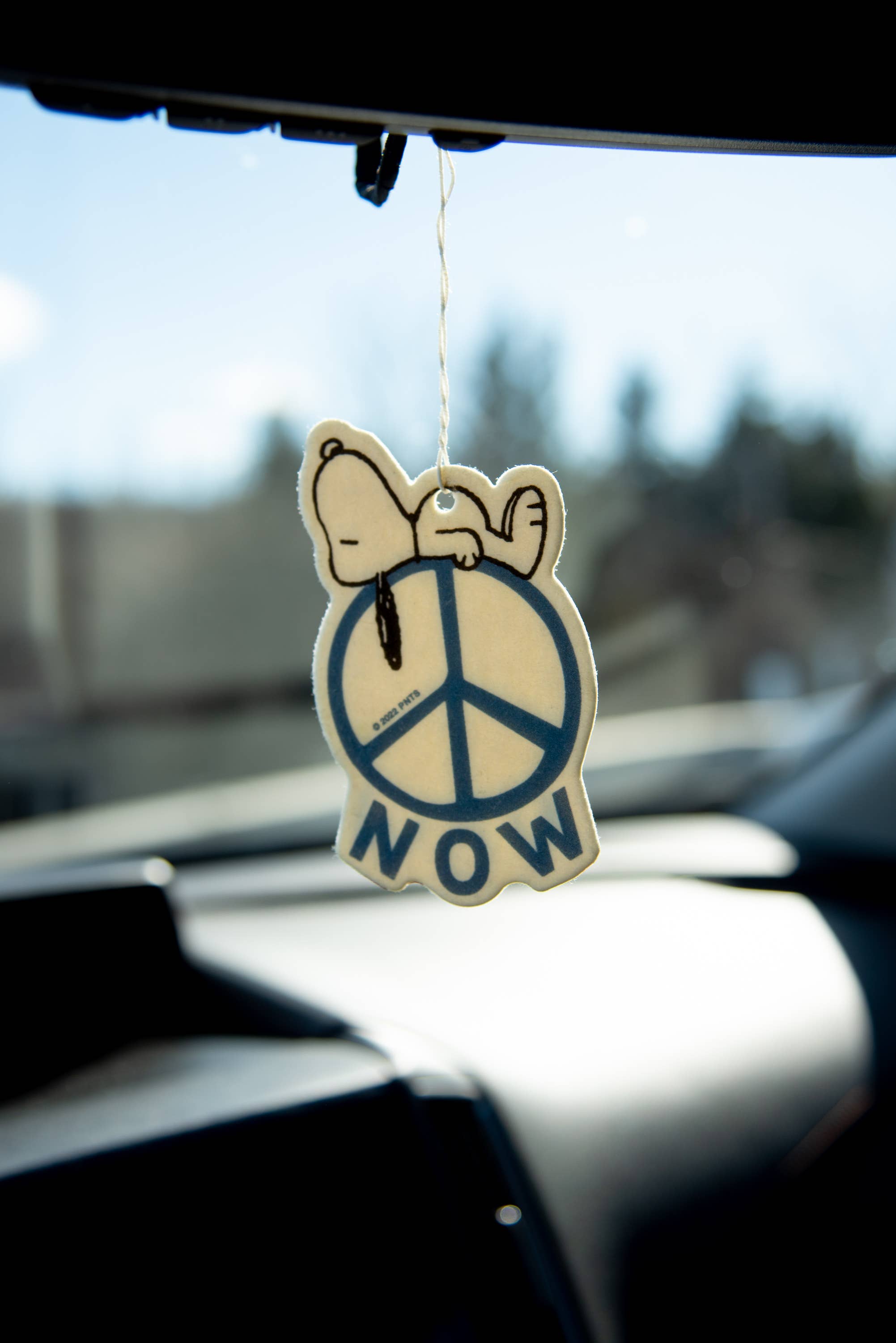 Peanuts® Snoopy Peace Now Air Freshener with fresh linen scent, featuring Snoopy resting on a peace sign.