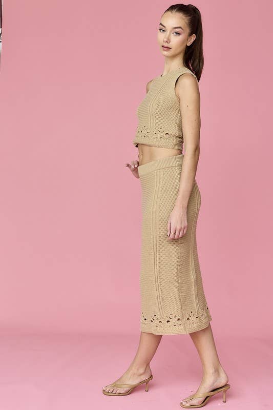 Woman wearing a beige sleeveless crochet top and midi skirt set.