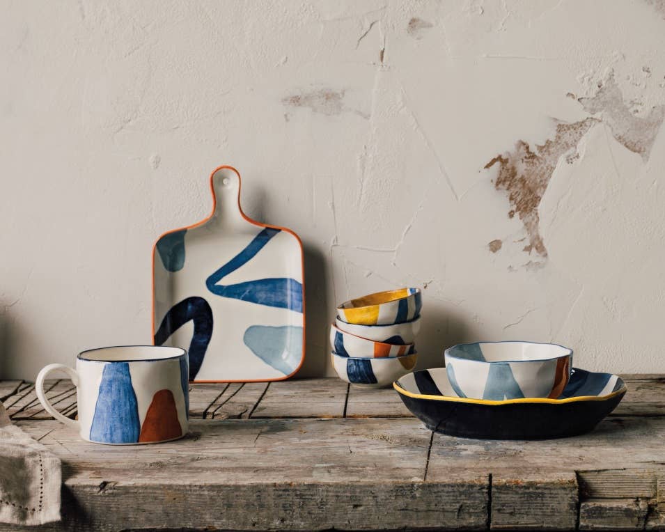 Hand-painted ceramic bowl with abstract mustard yellow, navy blue, and light blue patterns.