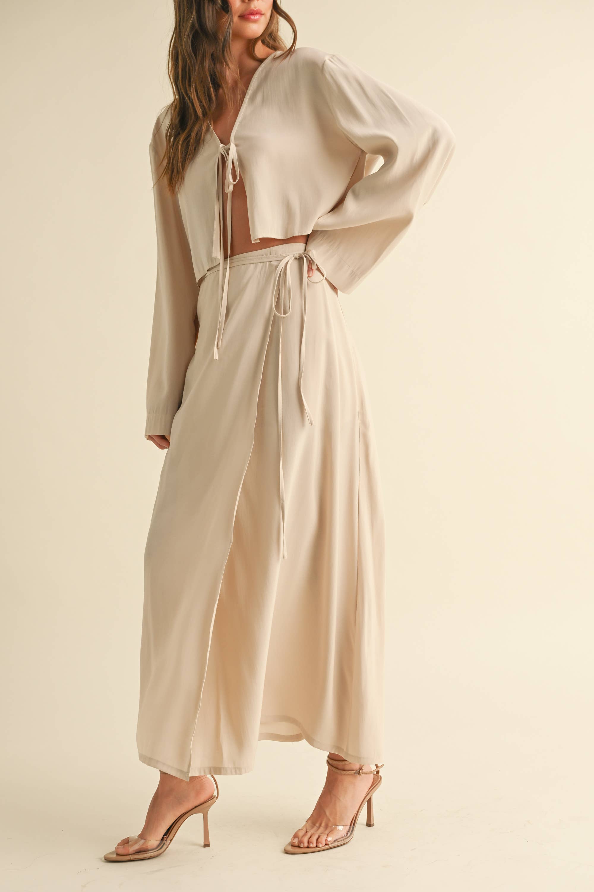 Woman wearing a beige tie-front long sleeve top and matching wrap maxi skirt, styled as a coordinated skirt set.