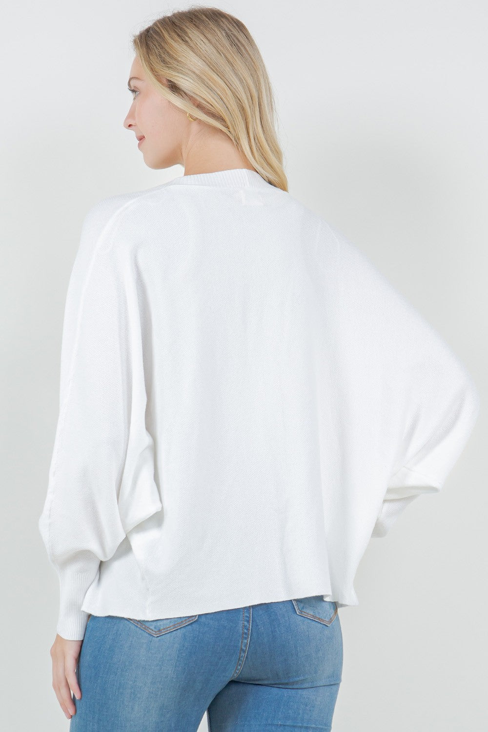 Woman wearing a white open-front cardigan with ribbed trim.
