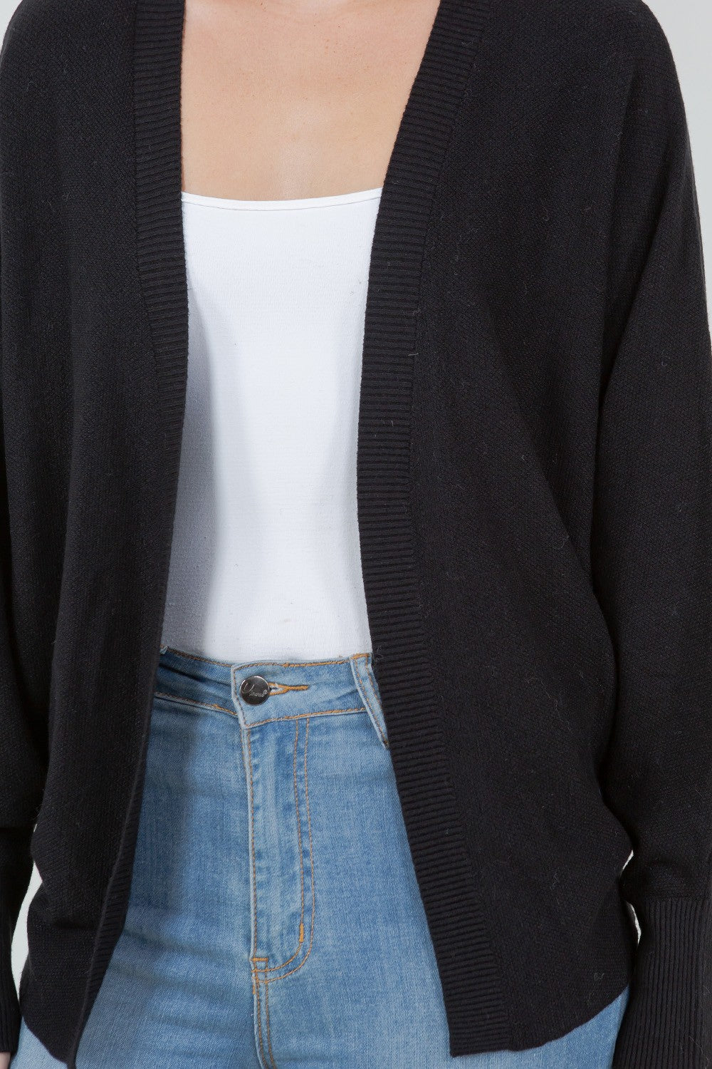 Woman wearing a black open-front cardigan with ribbed trim.