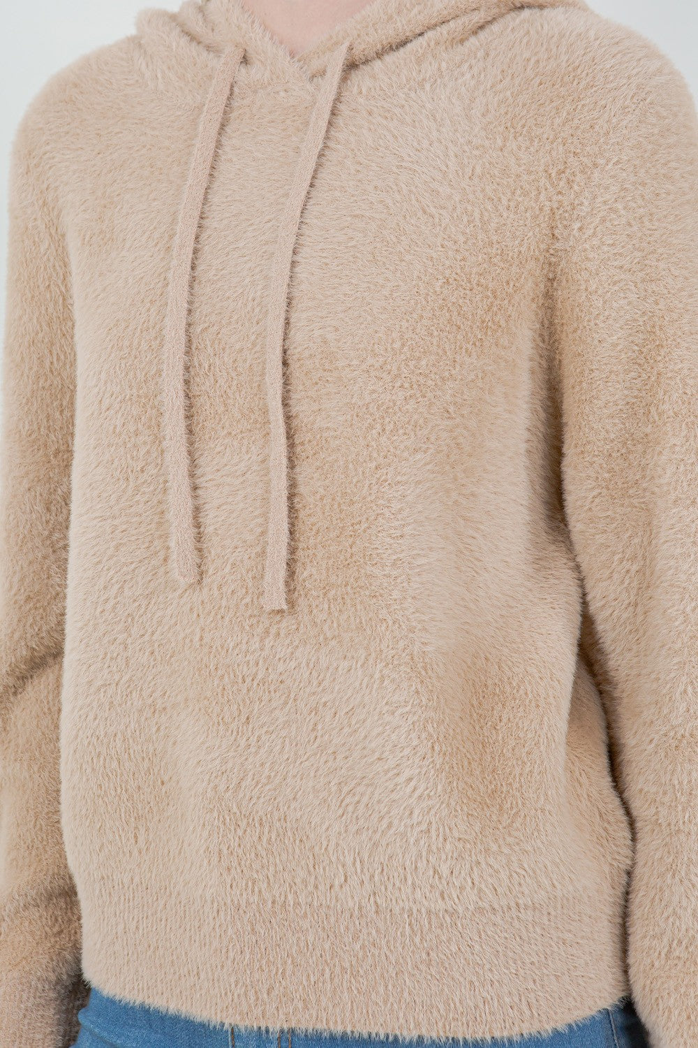 Woman wearing a beige ultra-soft hoodie with a drawstring hood.