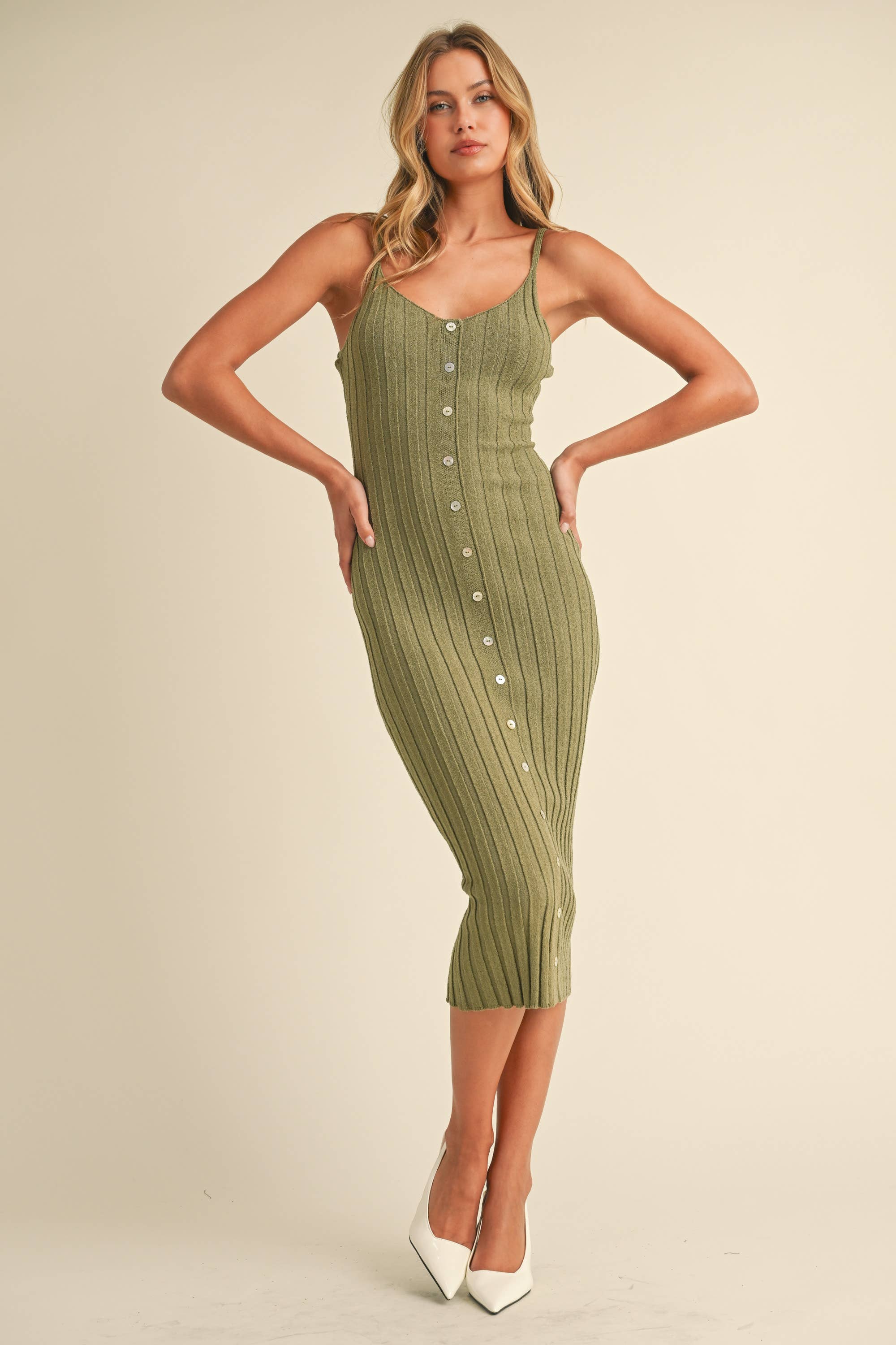 Woman wearing a sage green ribbed midi dress with spaghetti straps and front button detailing.