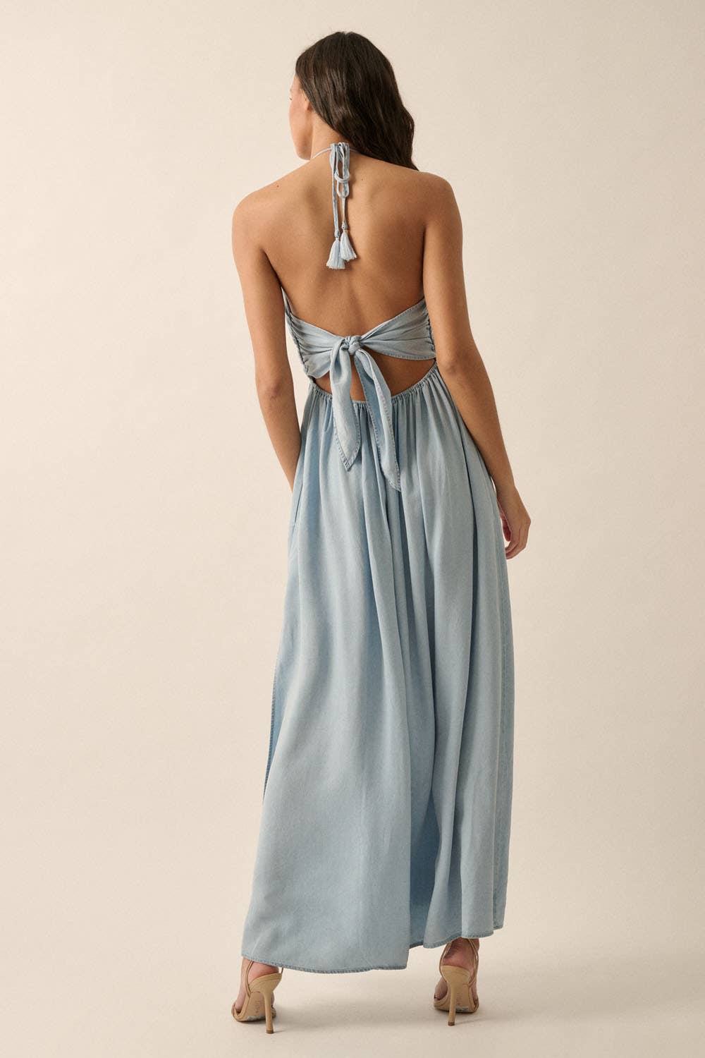Woman wearing a light blue halter maxi dress with a plunging neckline, side slit, and flowy fit.
