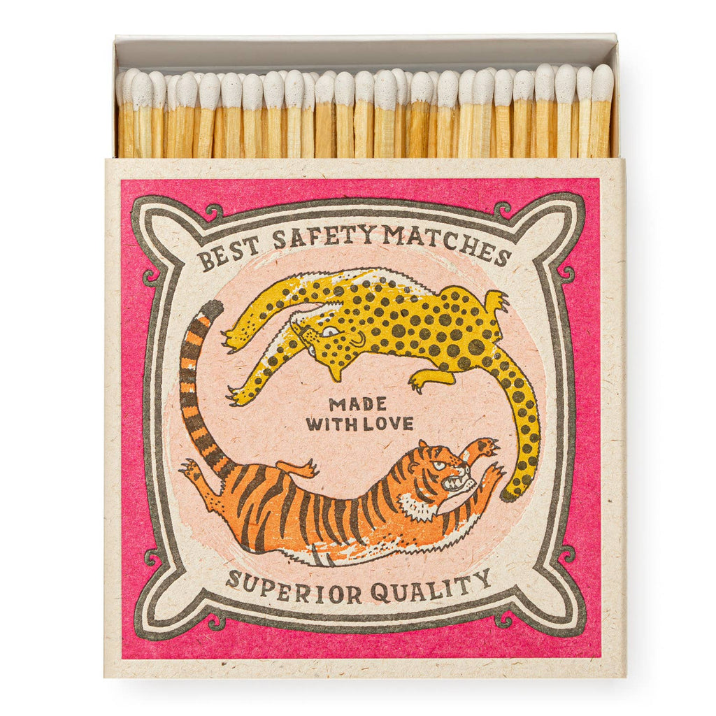 A square matchbox with a playful design depicting cats chasing each other.