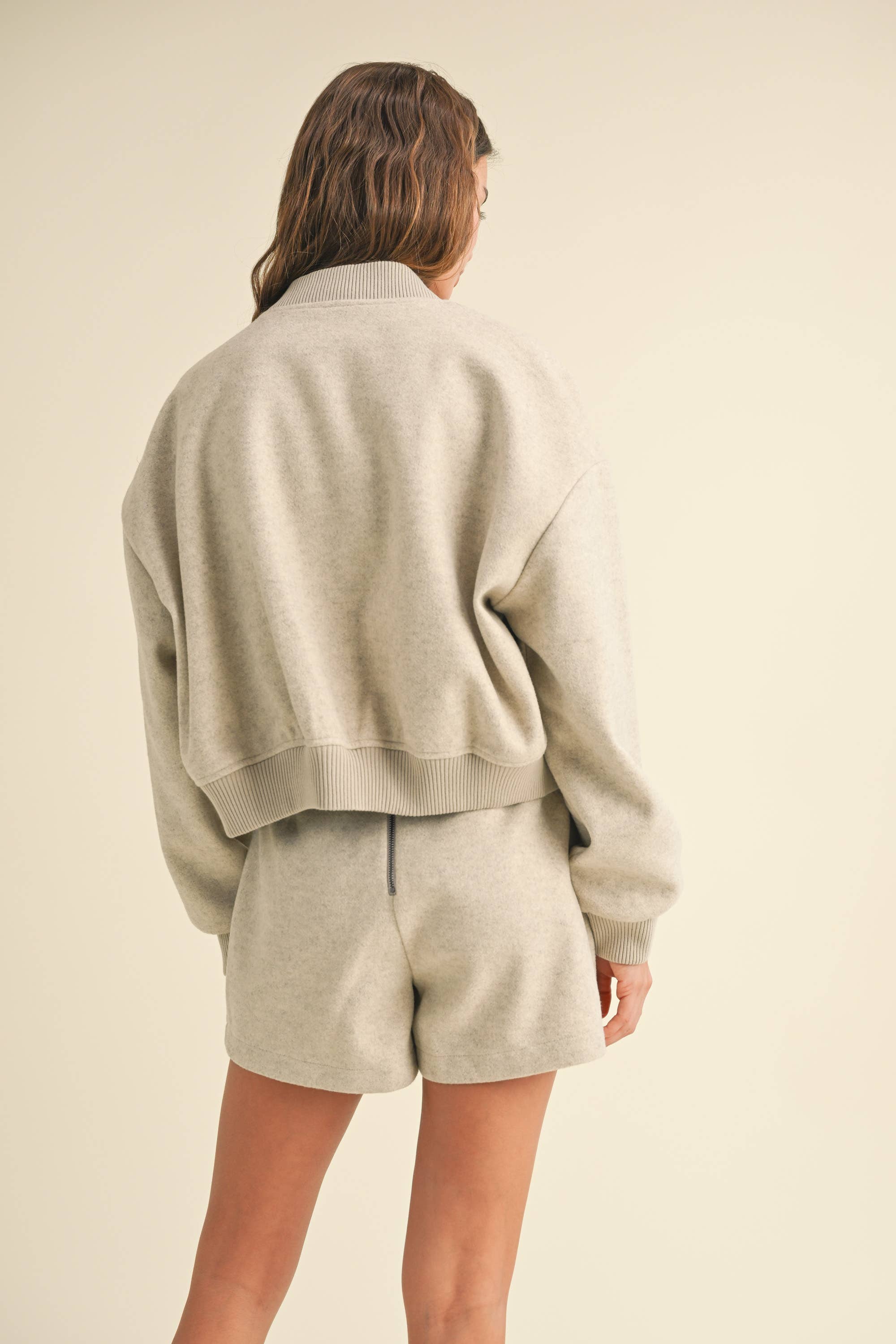 Model wearing a wool-blend jacket and mini skirt set in a neutral tone, styled with a striped tee and relaxed fit, showcasing casual elegance.