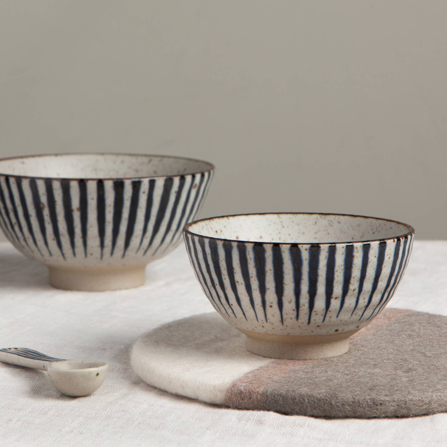 Two ceramic bowls with black stripes on a neutral background