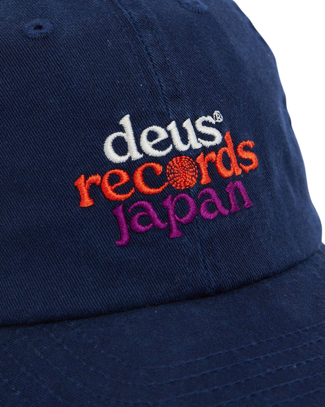 Navy blue cap with 'deus records Japan' embroidered text on a white background