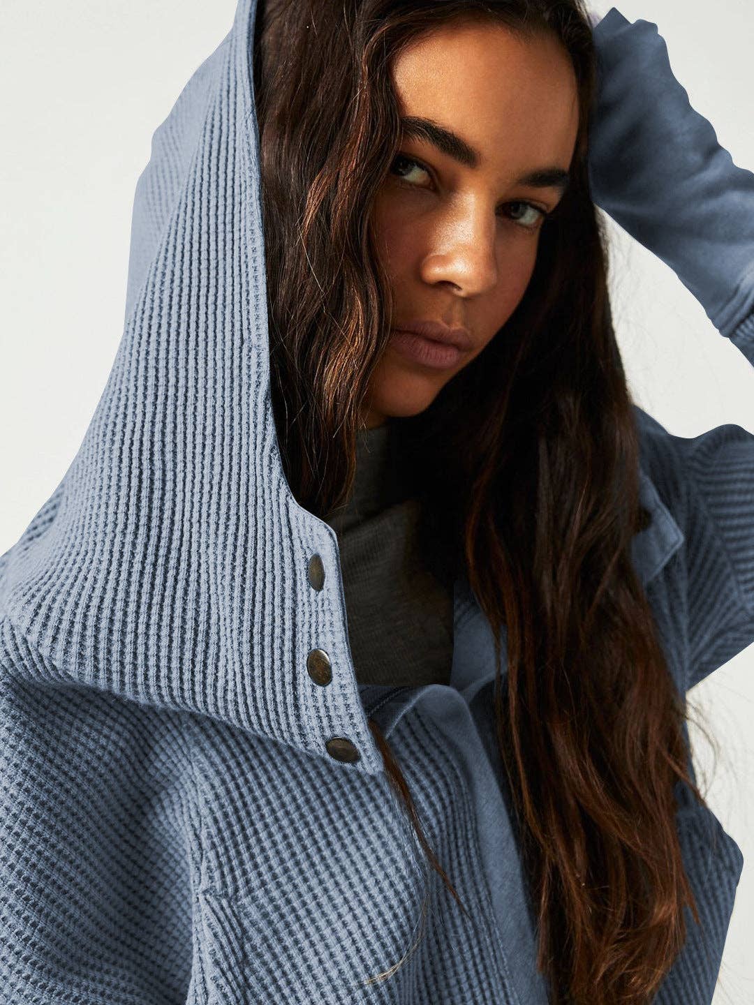 Woman wearing a Sahara Sky Hooded Jacket with a zip-up front, textured waffle knit, and button detailing in blue and brown tones.