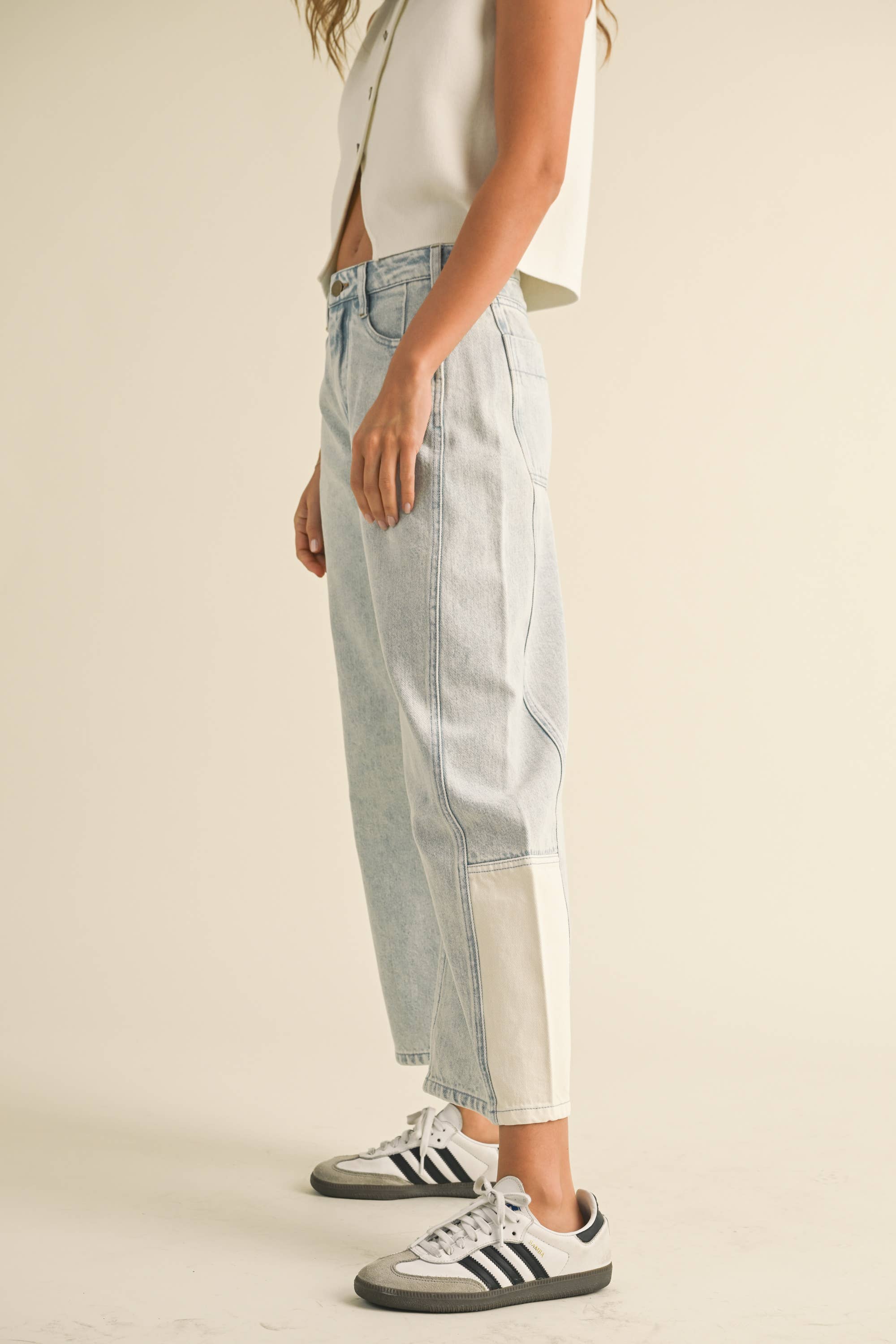 Model wearing light-wash wide-leg jeans with white contrast panels on the lower leg, styled with sneakers.