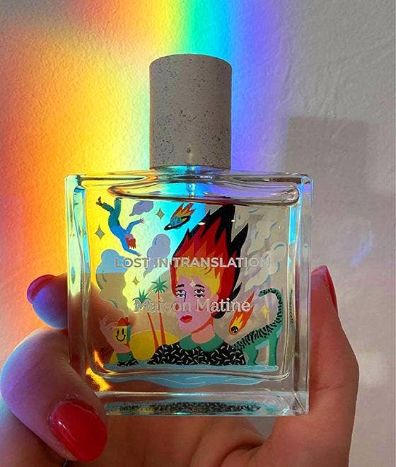 Maison Matine Lost in Translation perfume bottle with bold illustrated design, placed on vibrant yellow textured surface.