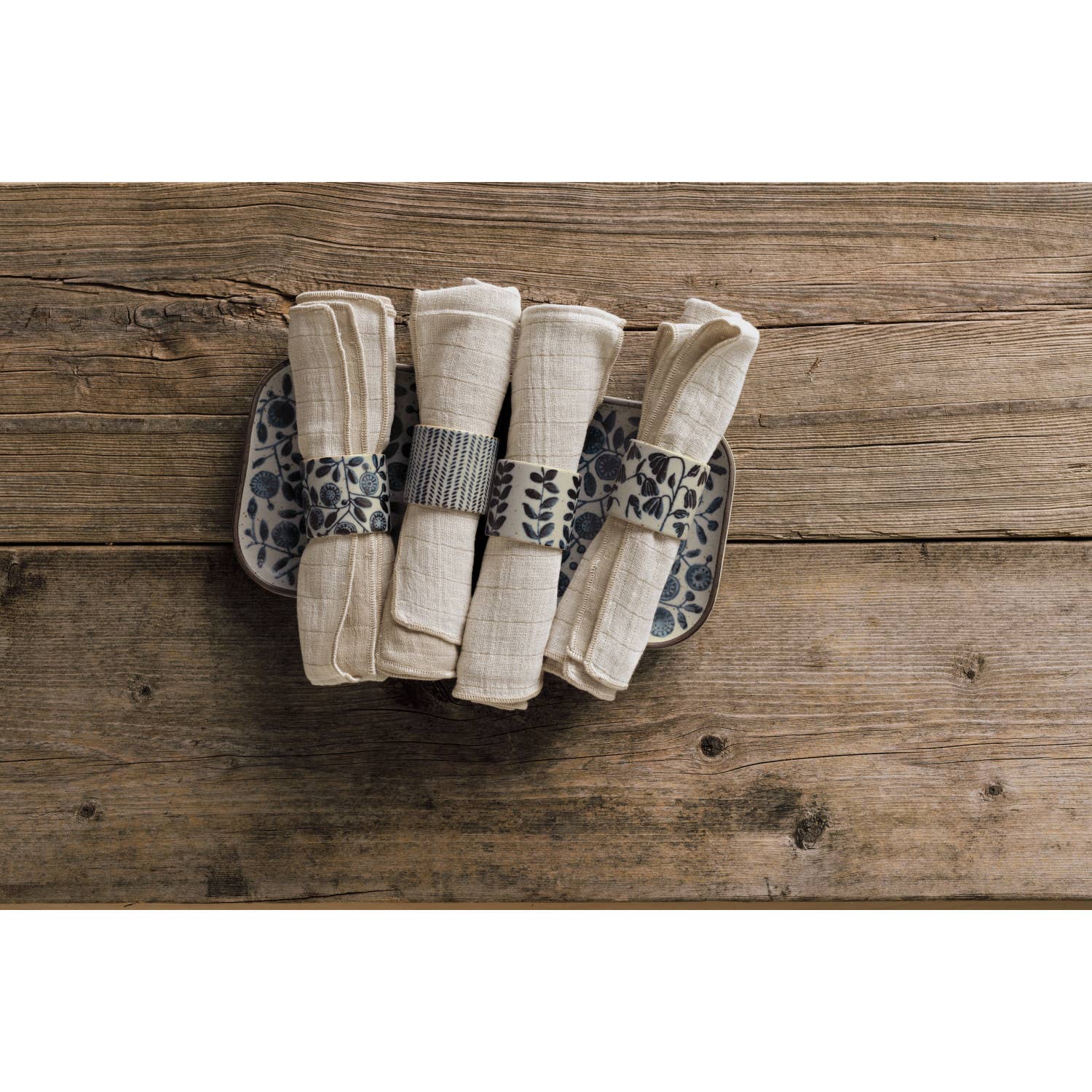 Set of folded napkins on a decorative plate with a floral pattern on a wooden surface