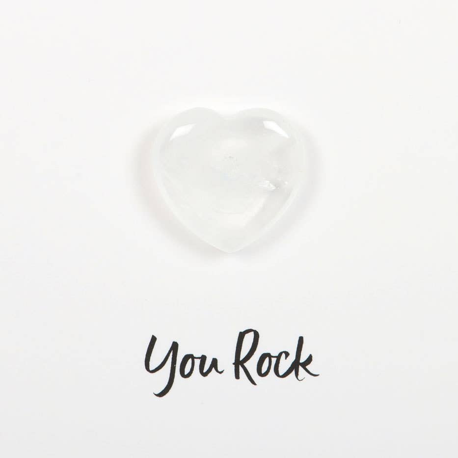 Hand holding a greeting card with a small clear quartz crystal heart and ‘You Rock’ text.
