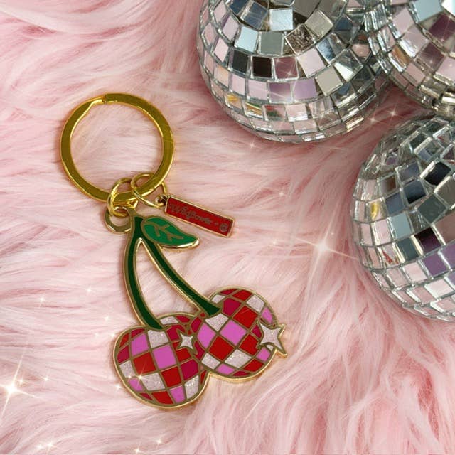 Disco Cherries Enamel Keychain featuring a pair of cherries with a sparkling, disco ball-inspired design on a pink background.