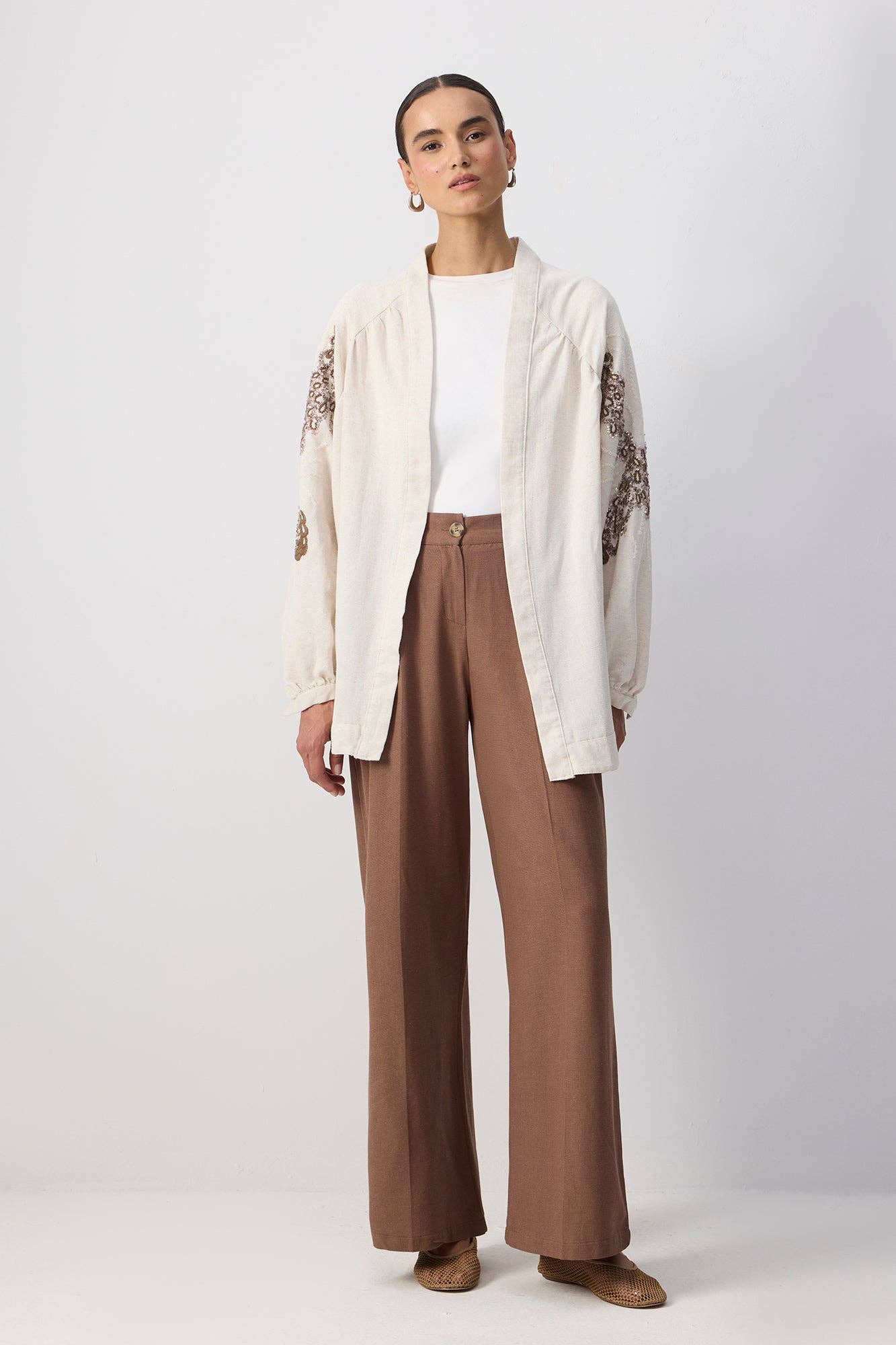 Back view of a woman wearing a cream embroidered kimono with sequin detailing and wide sleeves.