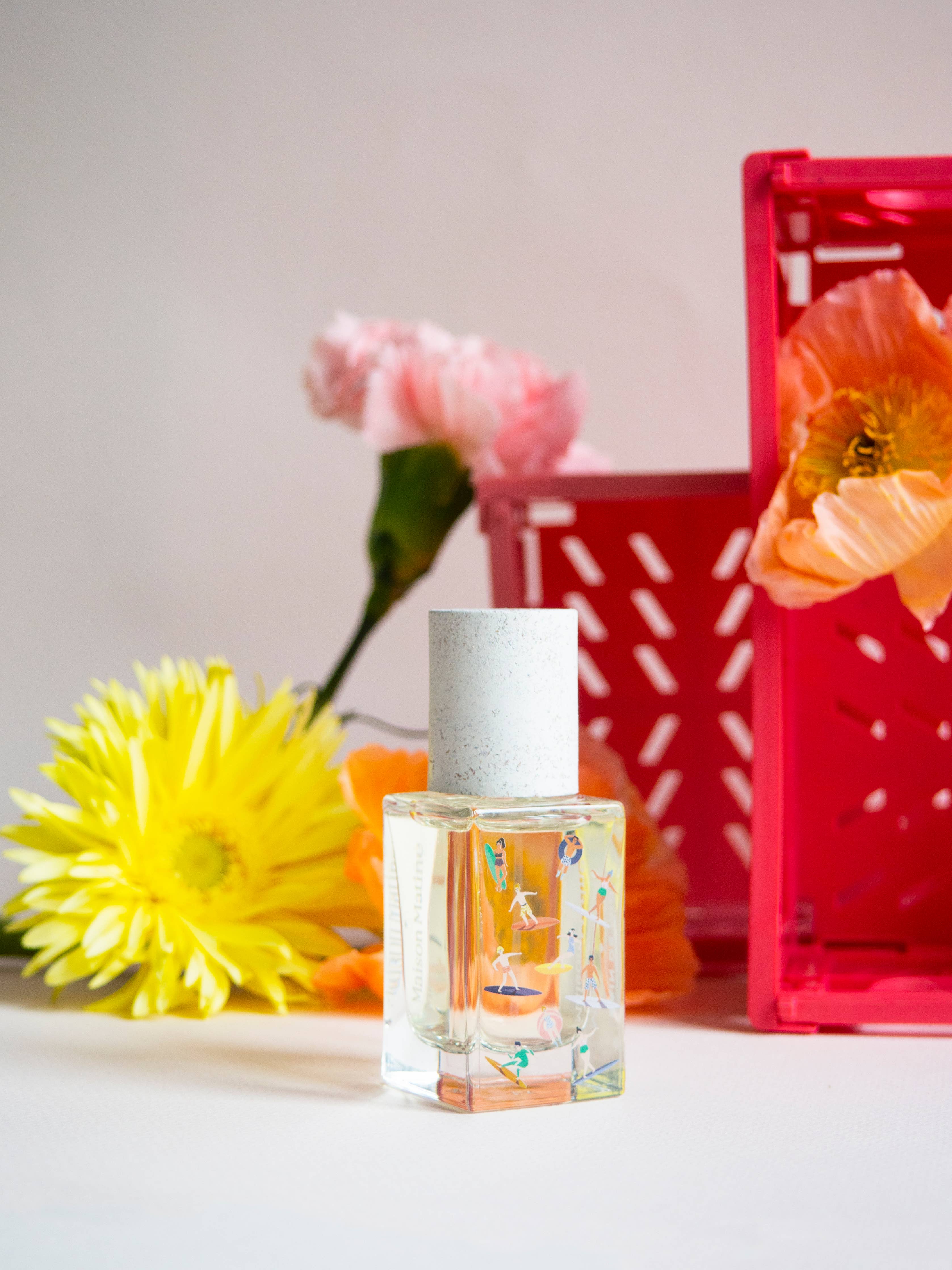 Maison Matine Bain de Midi perfume bottle styled with fresh flowers and a pink crate