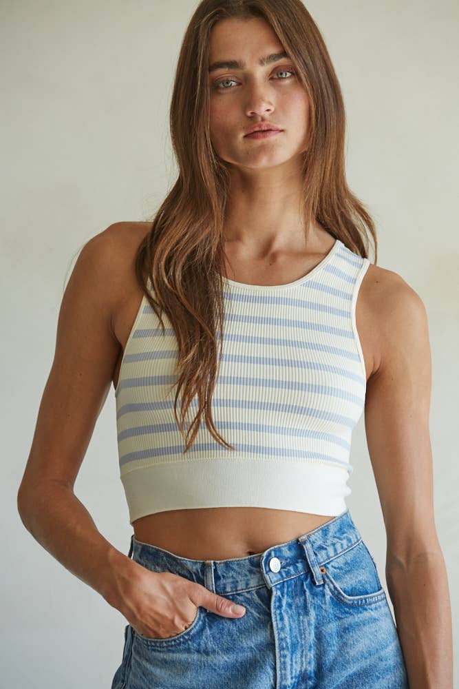 Model wearing a ribbed cropped racerback tank with navy and cream horizontal stripes, styled with an olive mini skirt.