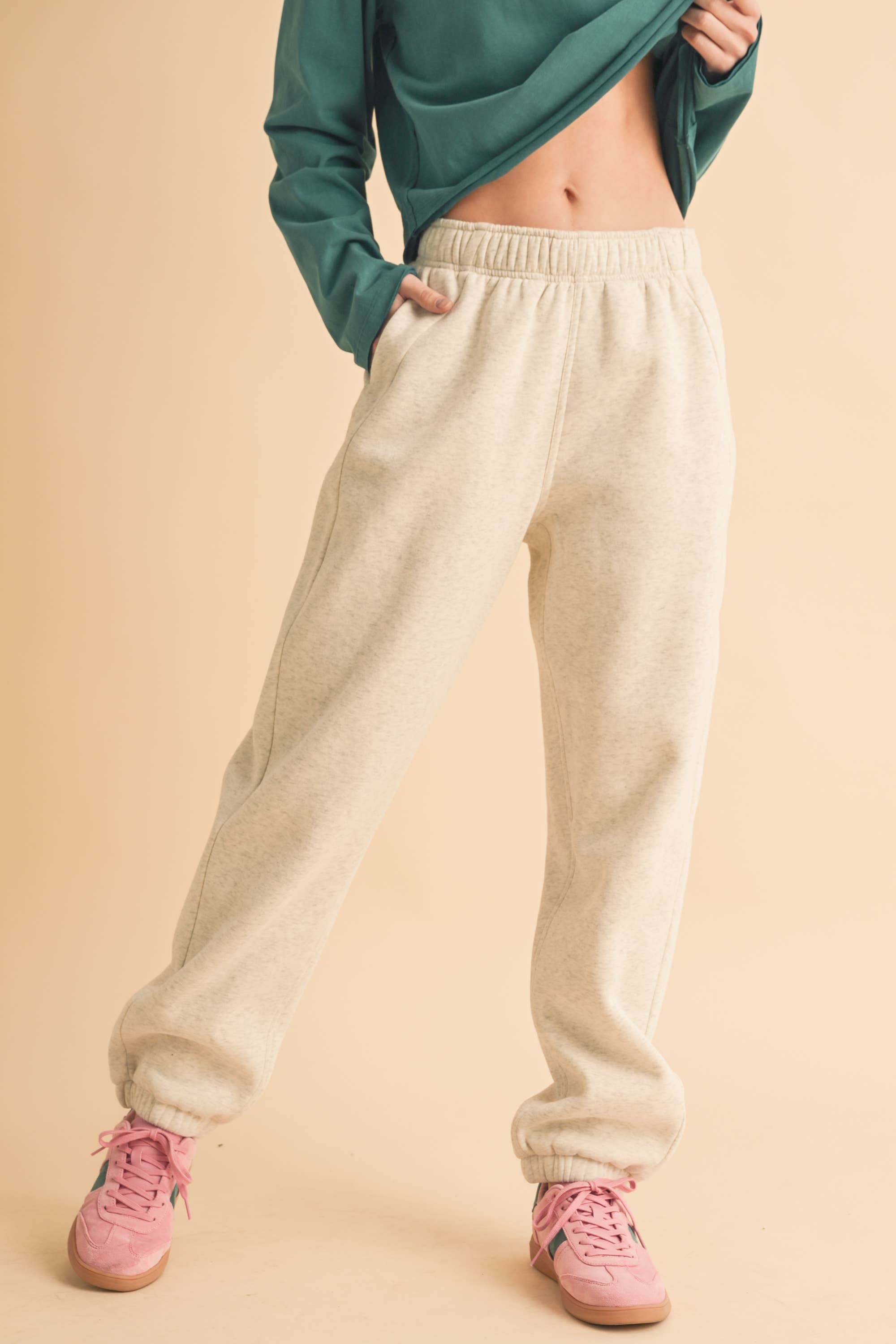 Woman wearing light heather beige fleece jogger pants with a relaxed fit and elastic waistband.