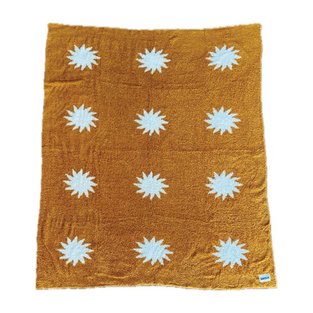 Cozy plush throw blanket in buckhorn brown with a white sunburst pattern, draped over a leather couch in a stylish and inviting living room.