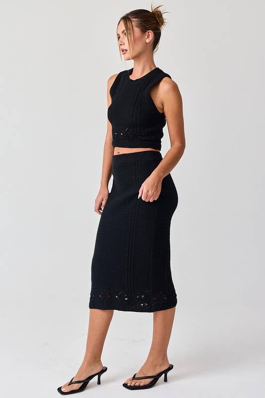 Woman wearing a black sleeveless crochet top and midi skirt set.
