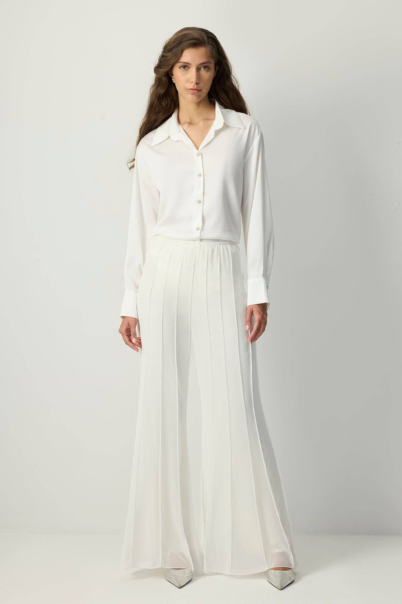 White pleated chiffon flared trousers with high waist and flowy wide legs.