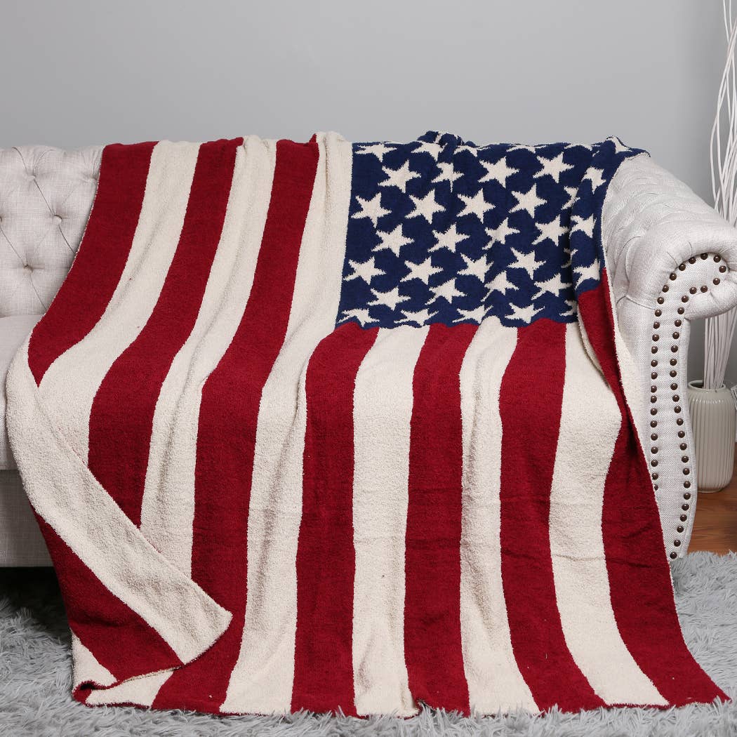 American flag patterned blanket draped over a white couch.
