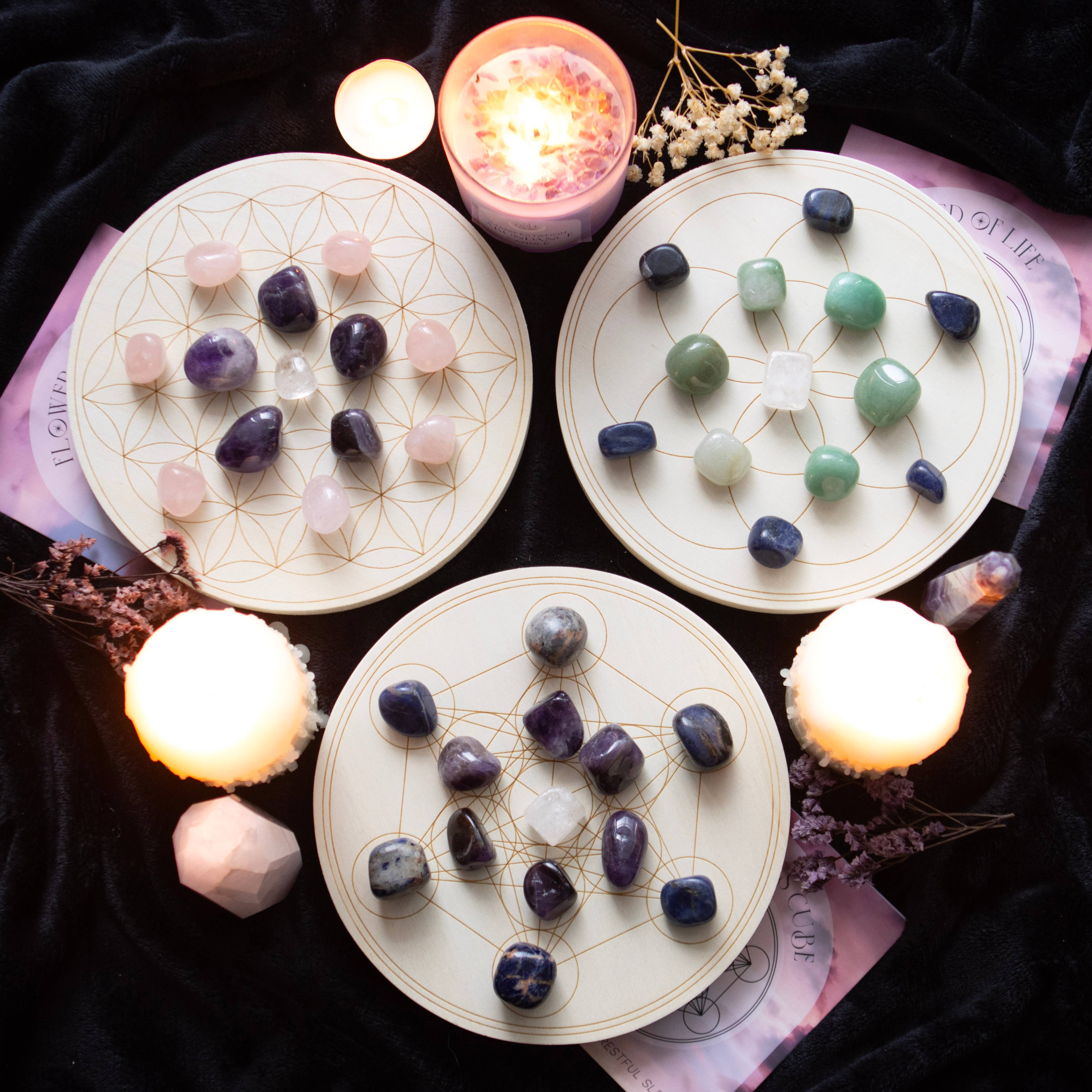 Seed of Life Crystal Grid Set featuring 6 sodalite tumblestones, 5 aventurine tumblestones, 1 clear quartz tumblestone, and an engraved wooden grid, surrounded by candles and decorative flowers.
