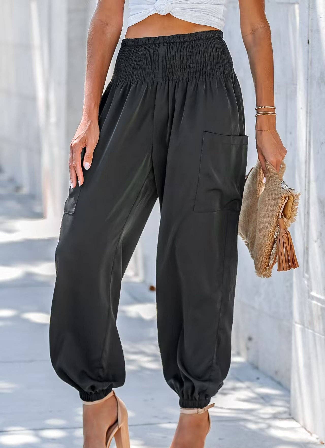 Woman wearing Serenity High-Waist Comfort Pants in beige and olive colors, paired with a white crop top and heels, carrying a decorative clutch.