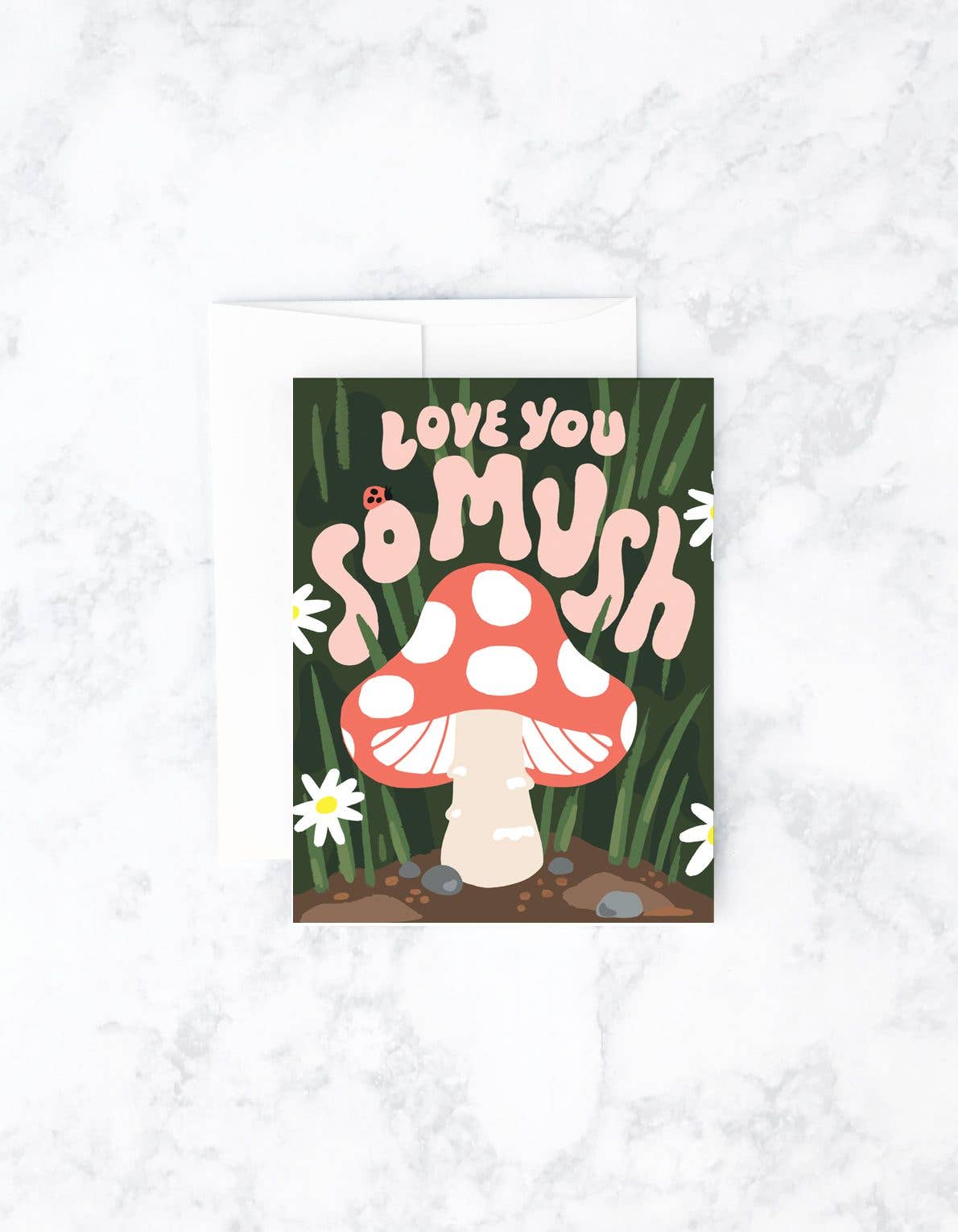 A greeting card with a hand-painted illustration of a mushroom and the text 'love you so mush' on a background that resembles a garden.