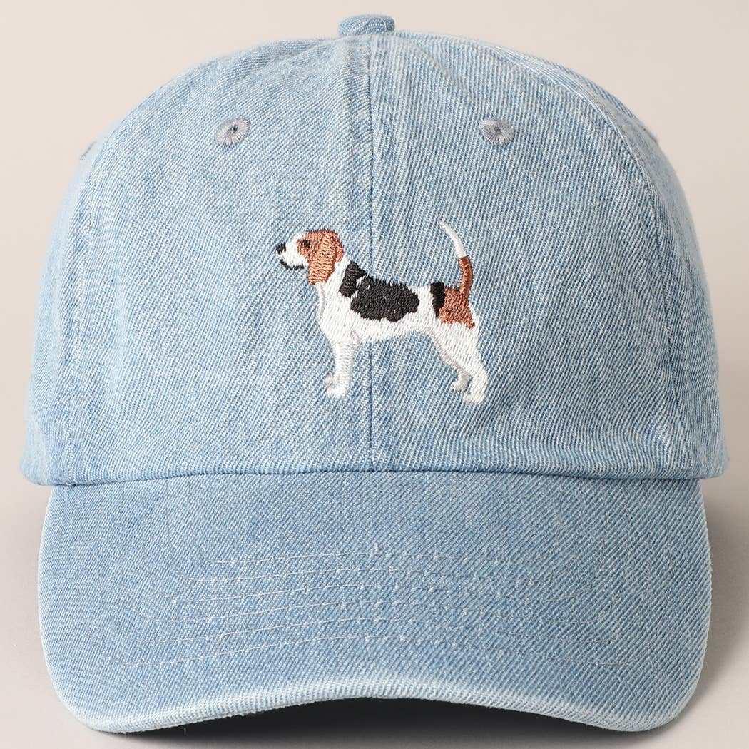 Light blue denim cap with embroidered dog design on a beige background