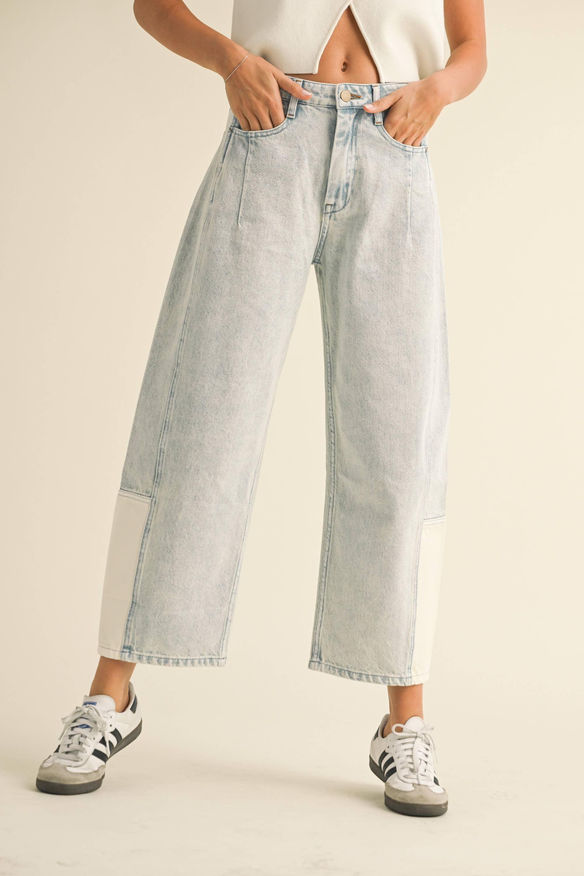 Model wearing light-wash wide-leg jeans with white contrast panels on the lower leg, styled with sneakers.
