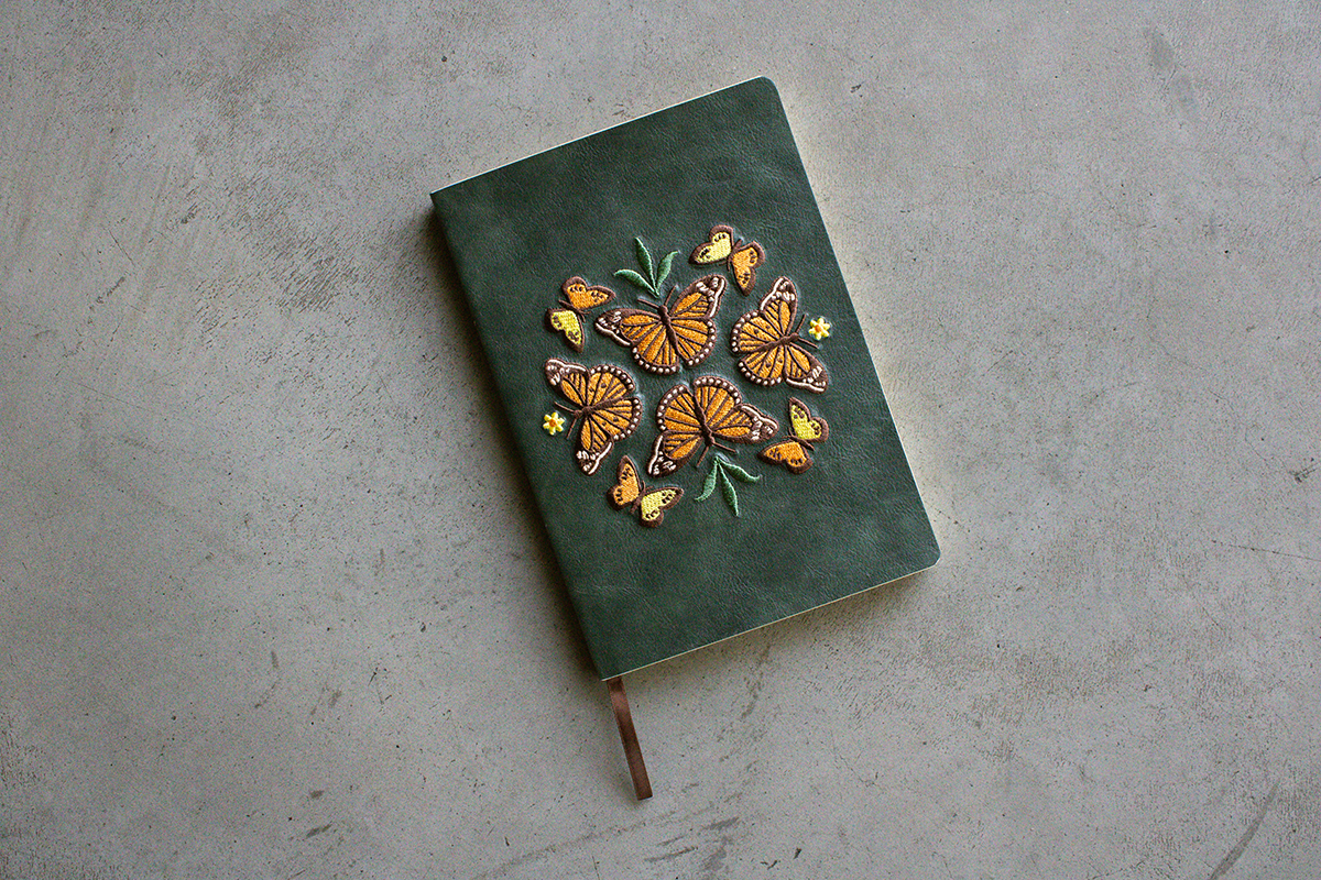 Green notebook with embroidered monarch butterfly design.