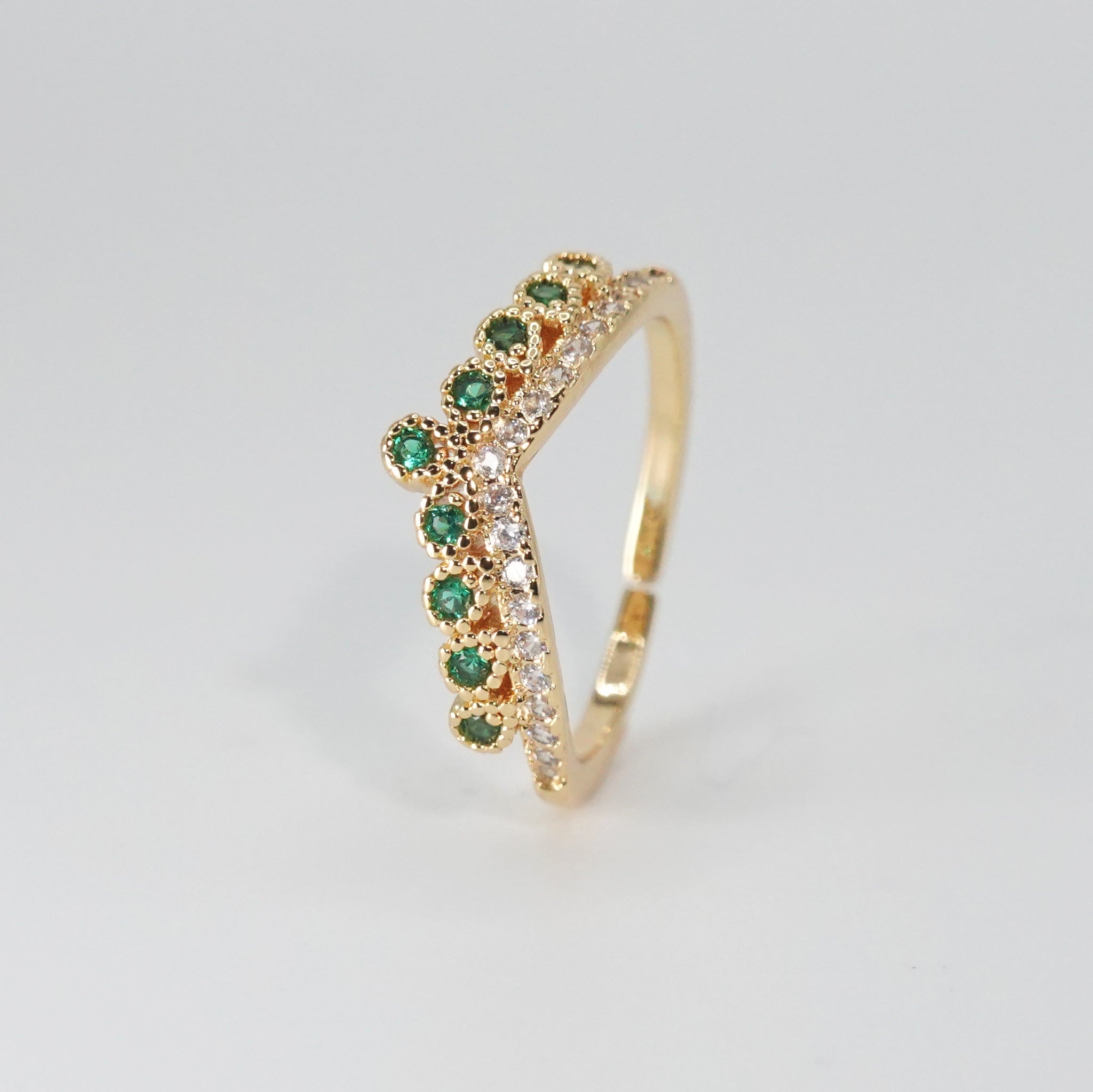 Virginia Ring: Majestic crown-shaped design adorned with shimmering and verdant green stones, epitome of regal elegance.