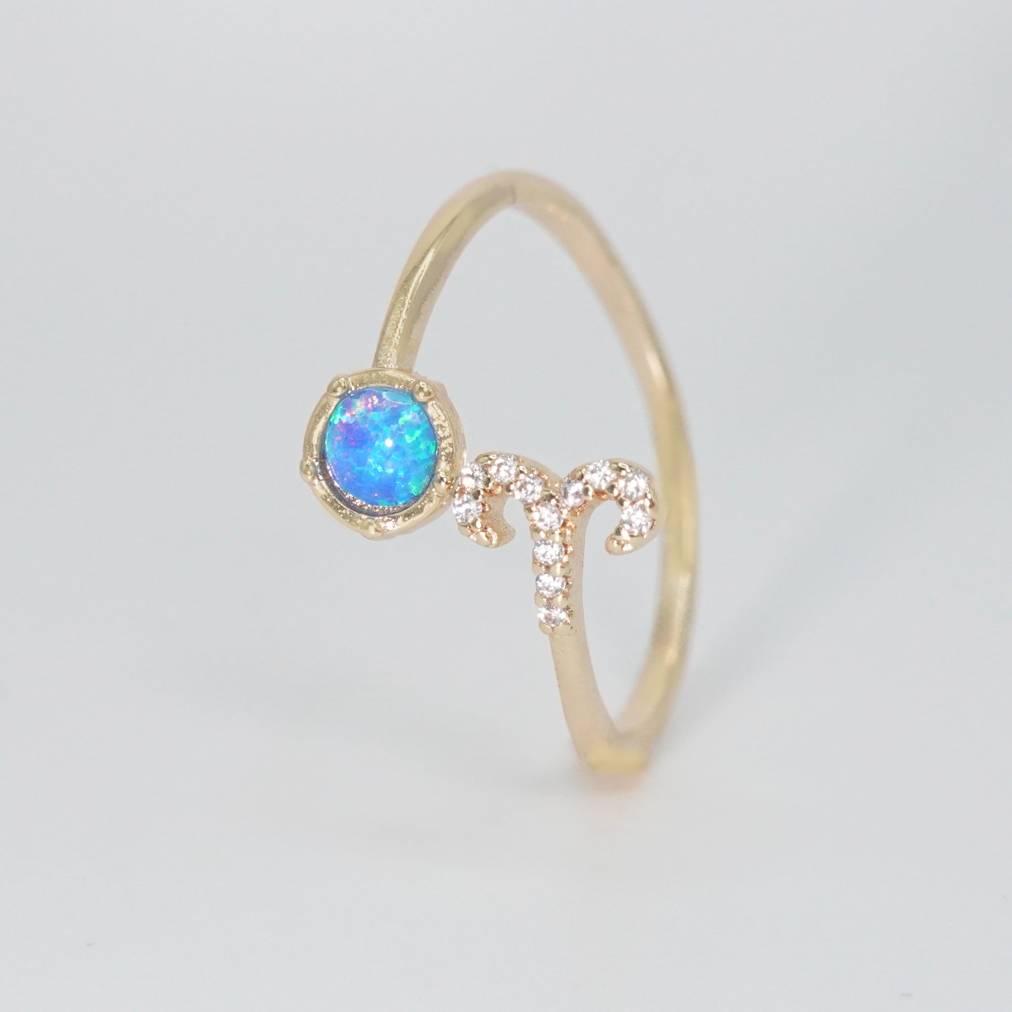 Aries Ring: Ram symbol with shimmering stones surrounding an opal, embodying fiery spirit.