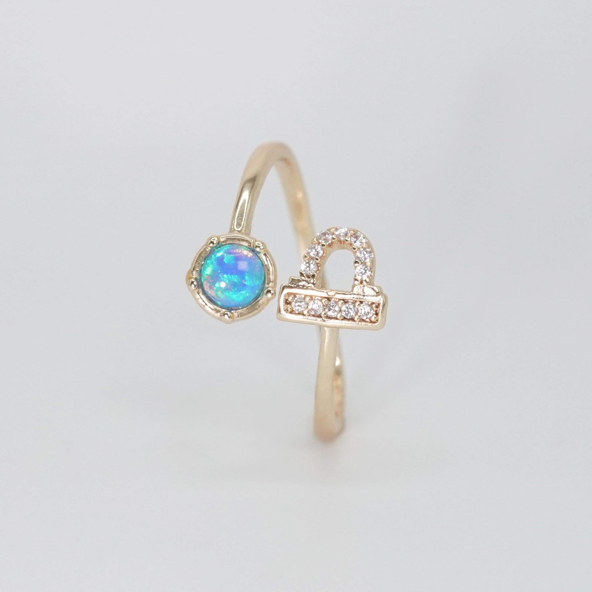 Libra Ring: Scales symbol with shimmering stones surrounding an opal, epitome of balance.