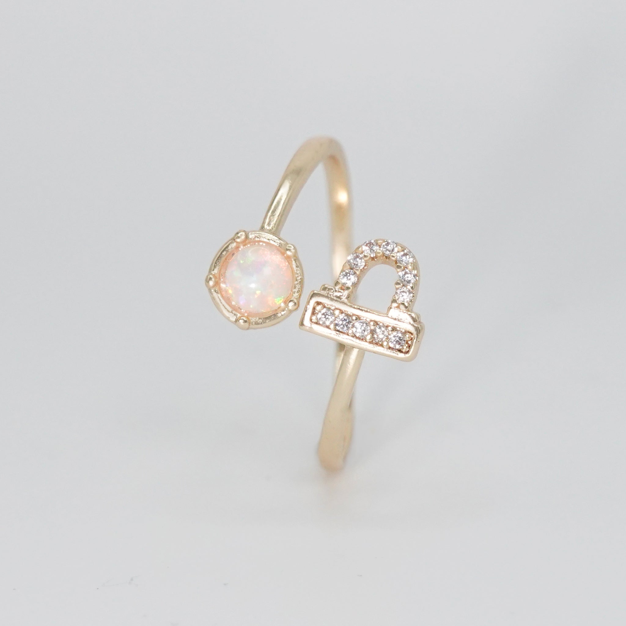 Libra Ring: Scales symbol with shimmering stones surrounding an opal, epitome of balance.