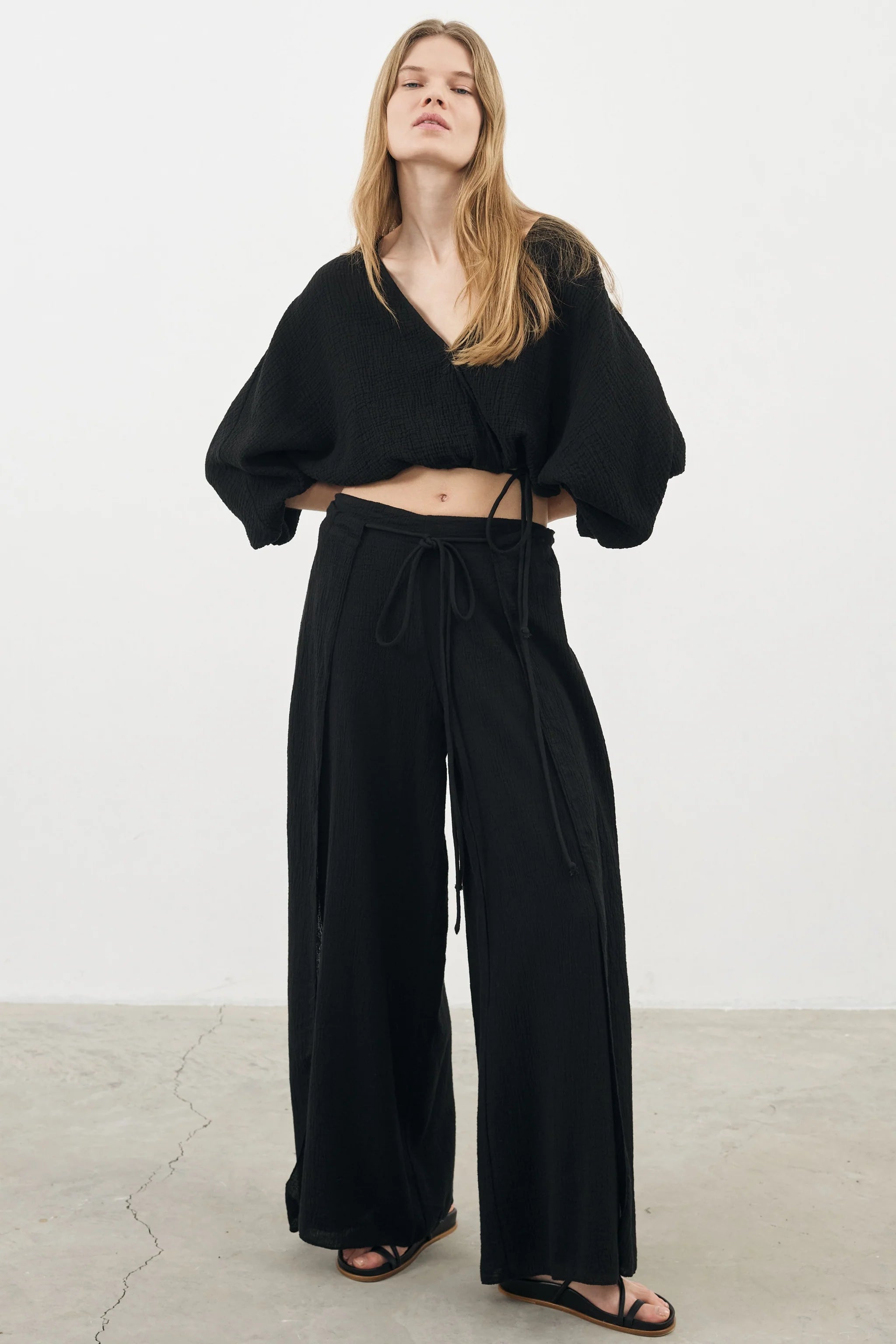Siena Top displayed on a hanger, showcasing its wide sleeves and the unique V-shaped front drape with a hidden optional closure.