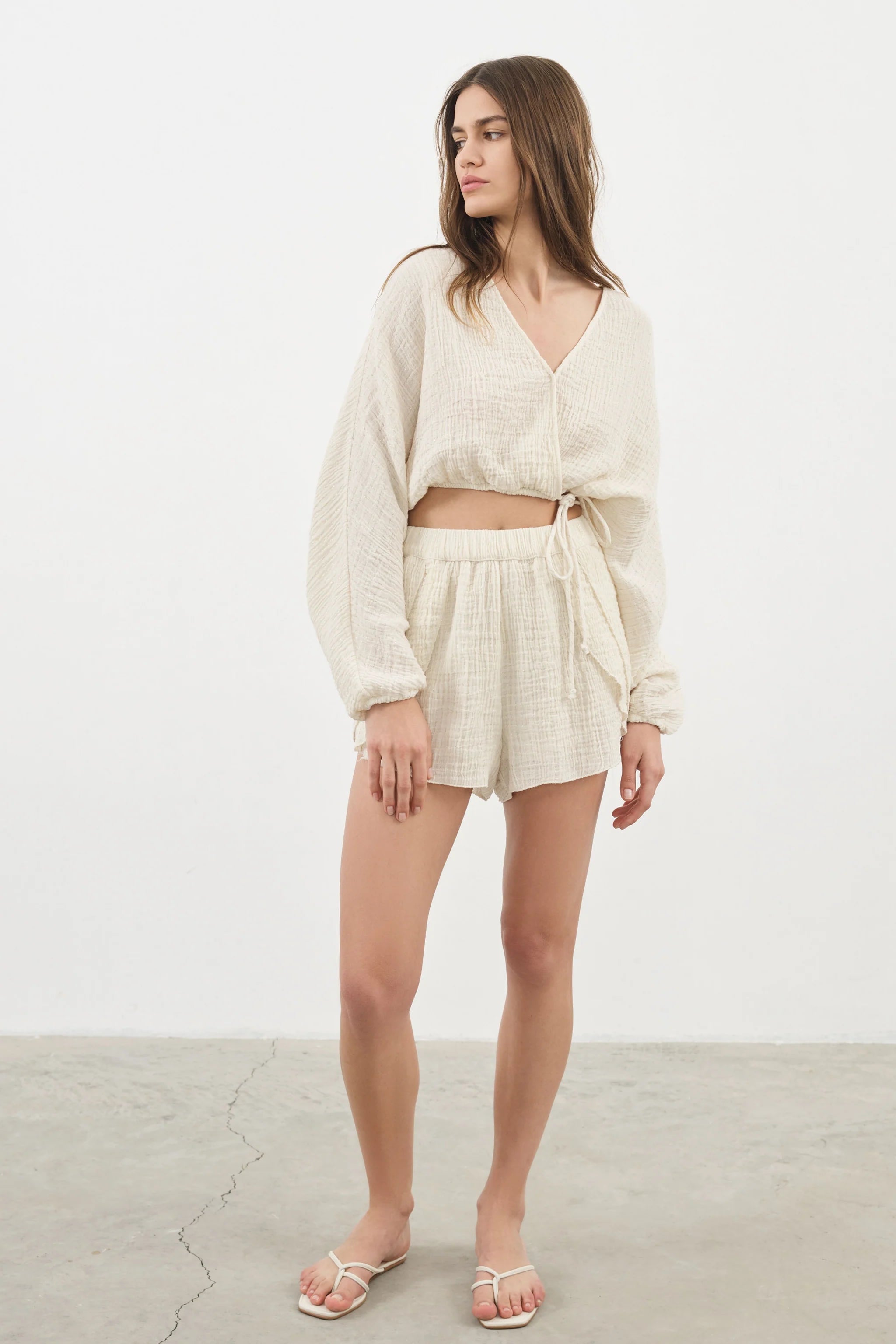Siena Top displayed on a hanger, showcasing its wide sleeves and the unique V-shaped front drape with a hidden optional closure.