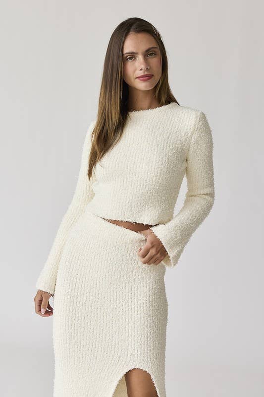 Woman wearing a white round neck long sleeve crop soft knit top and midi skirt set with a side slit.