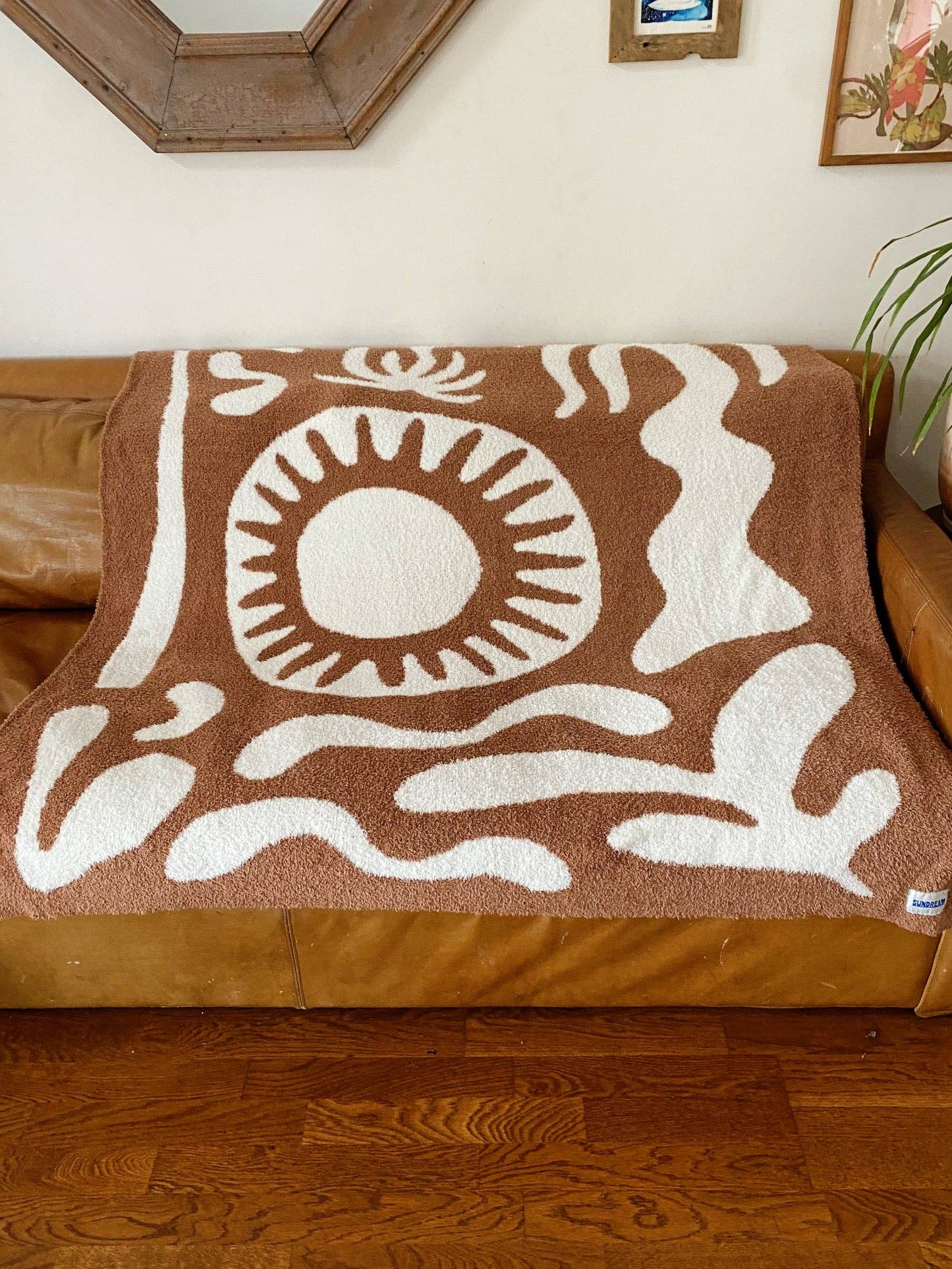 Soft brown plush throw blanket with a sun and palm tree design, perfect for adding warmth and a stylish accent to any space.