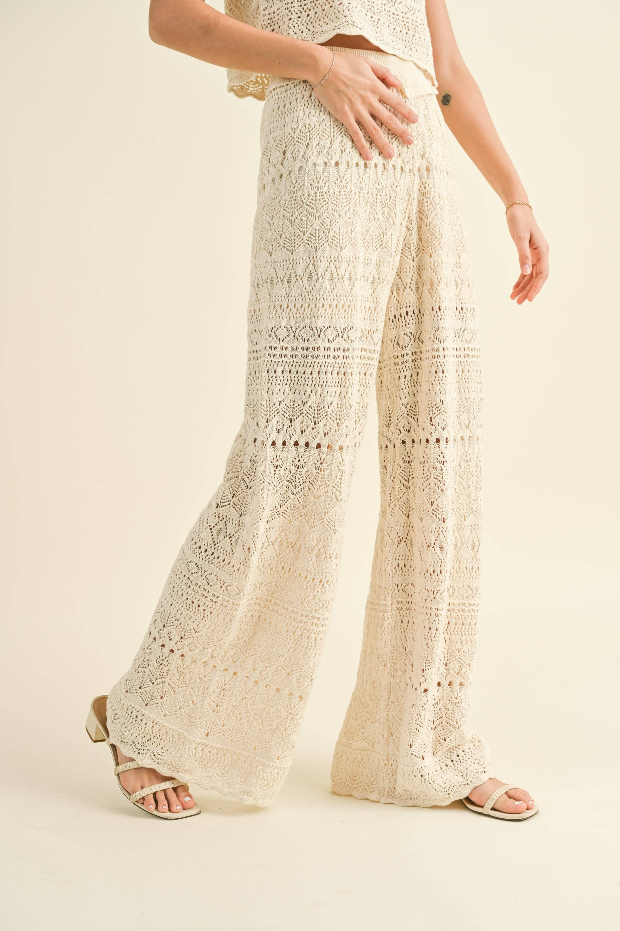 Model wearing cream-colored crochet wide-leg pants with intricate patterns and a high waist.