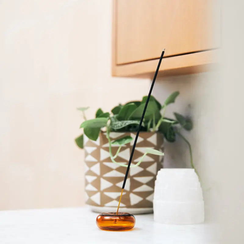 Elegant Amber & Moss Incense sticks meticulously arranged in a stylish holder, beautifully poised against a calming background.