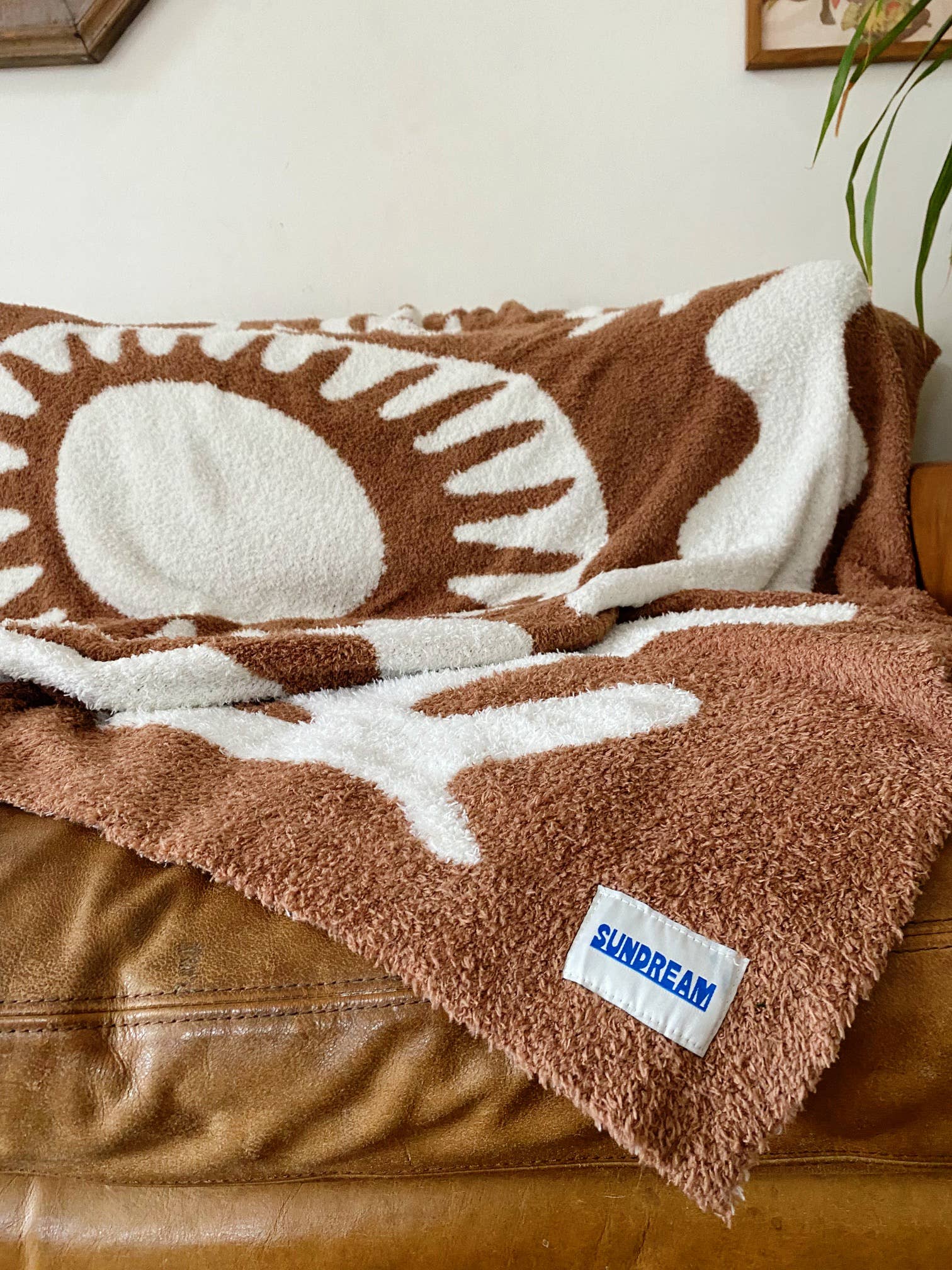 Soft brown plush throw blanket with a sun and palm tree design, perfect for adding warmth and a stylish accent to any space.