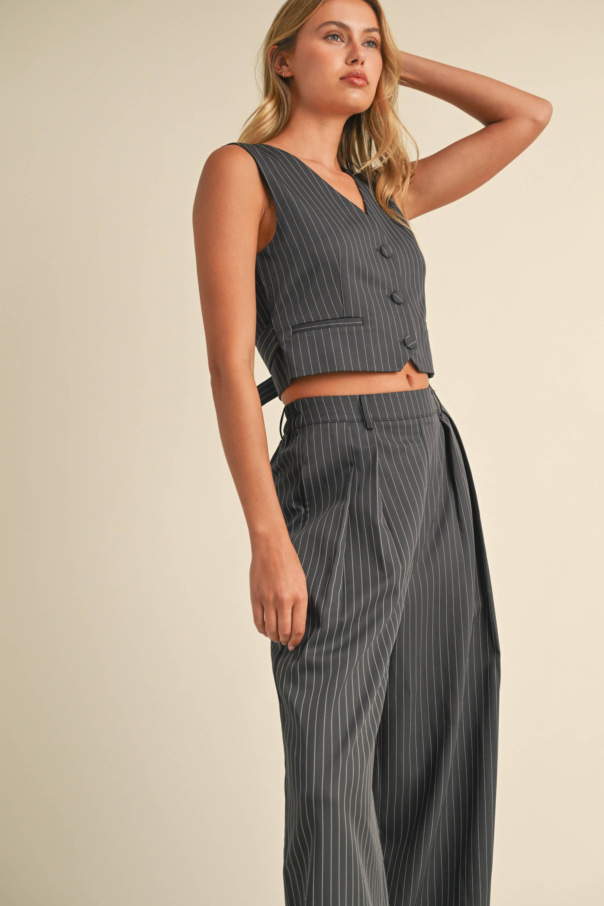 Woman wearing a sleeveless pinstriped vest and matching high-waisted wide-leg trousers.