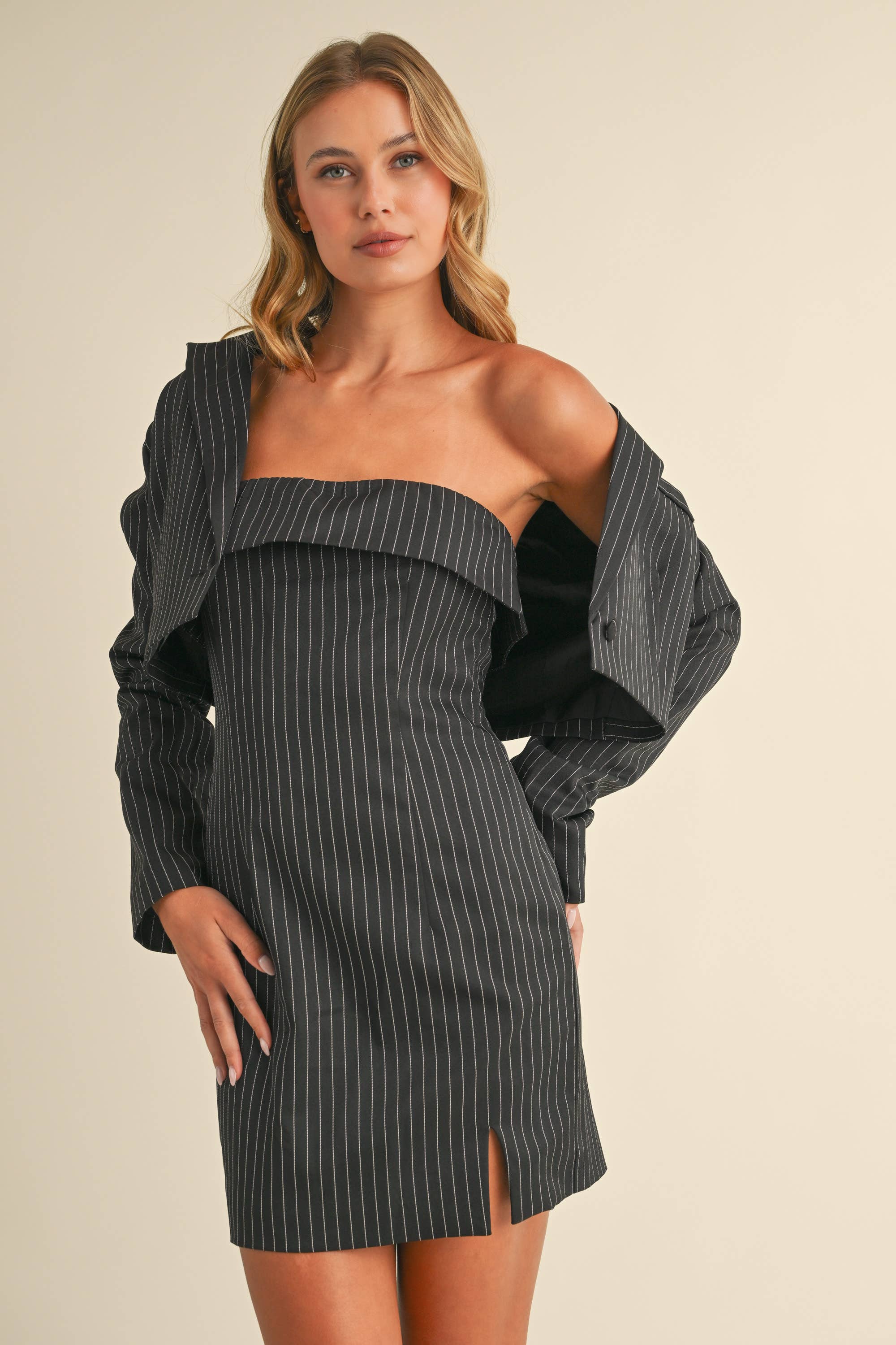 Woman wearing a black pinstriped strapless midi dress with a matching cropped blazer jacket.